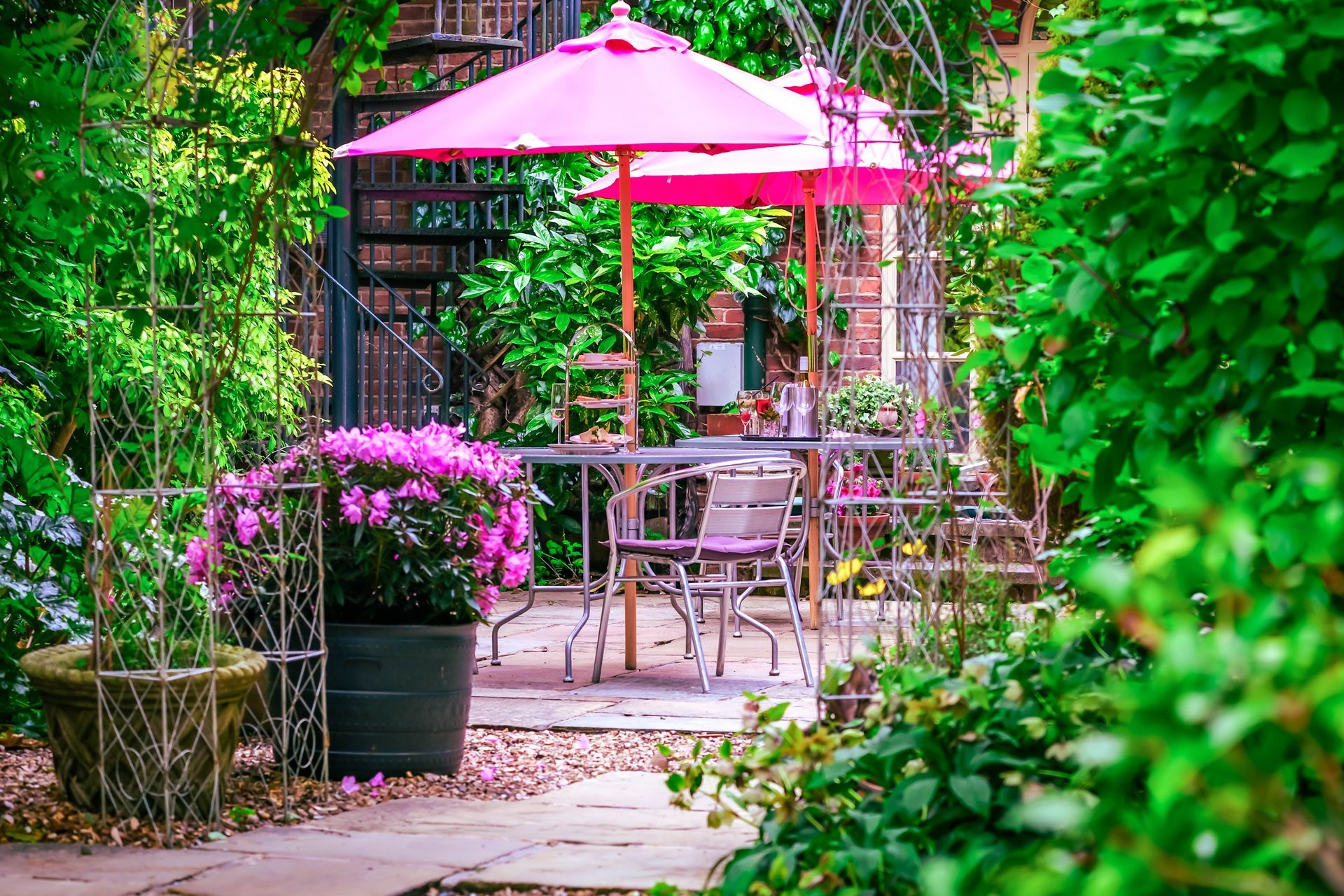 A pink umbrella is sitting on top of a table in a garden.