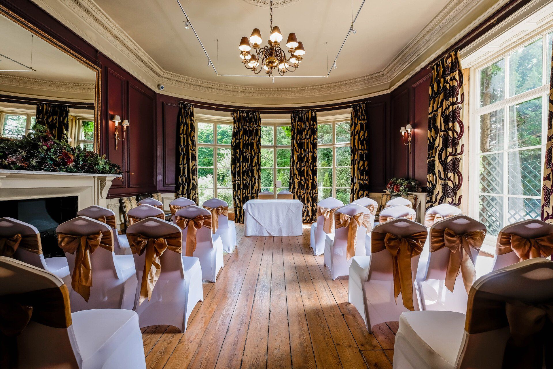 A room with chairs and a table set up for a wedding ceremony.