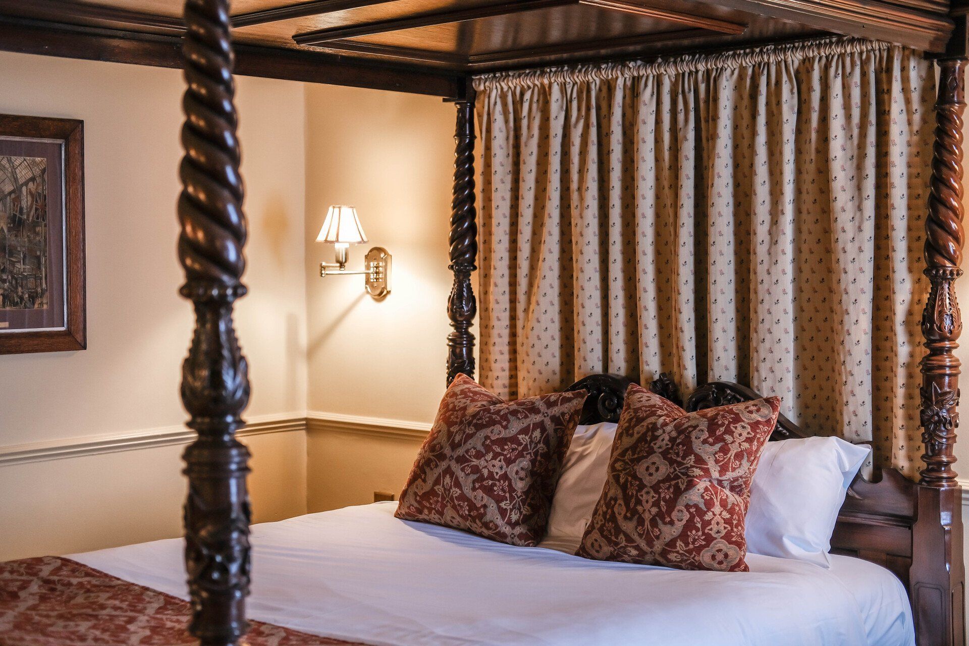 A four poster bed with pillows and curtains in a bedroom.
