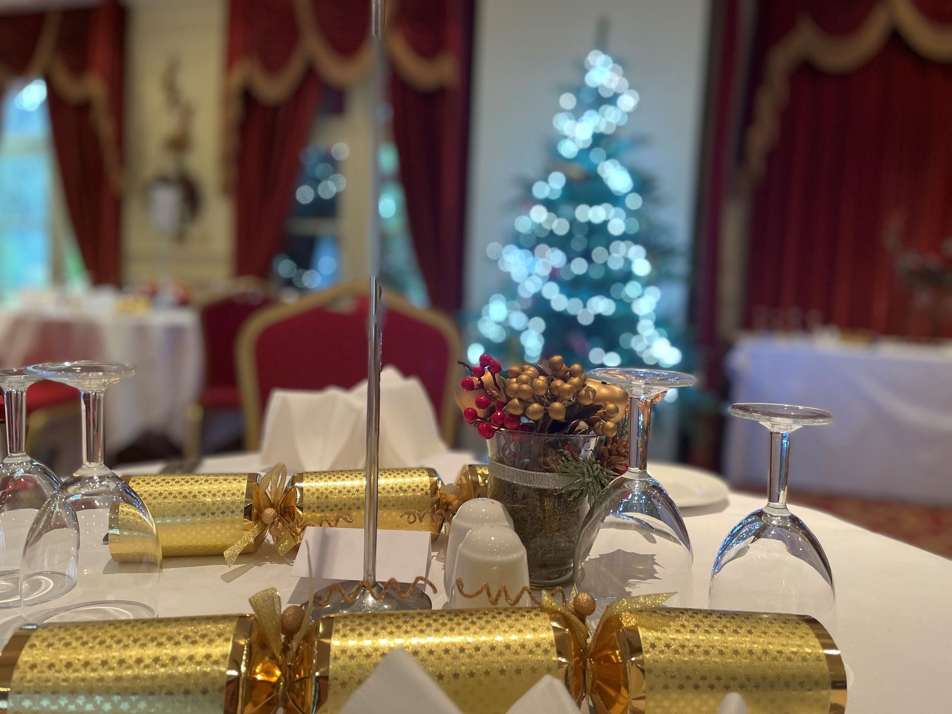 A table set for a christmas dinner with a christmas tree in the background.