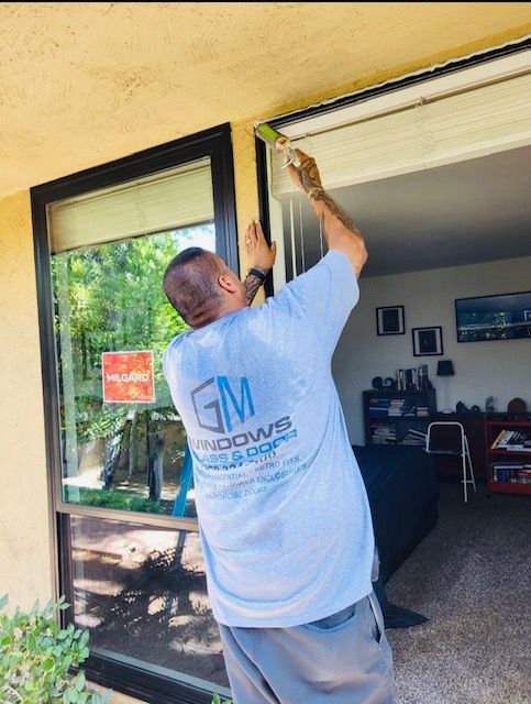 A man wearing a gm windows shirt is working on a window