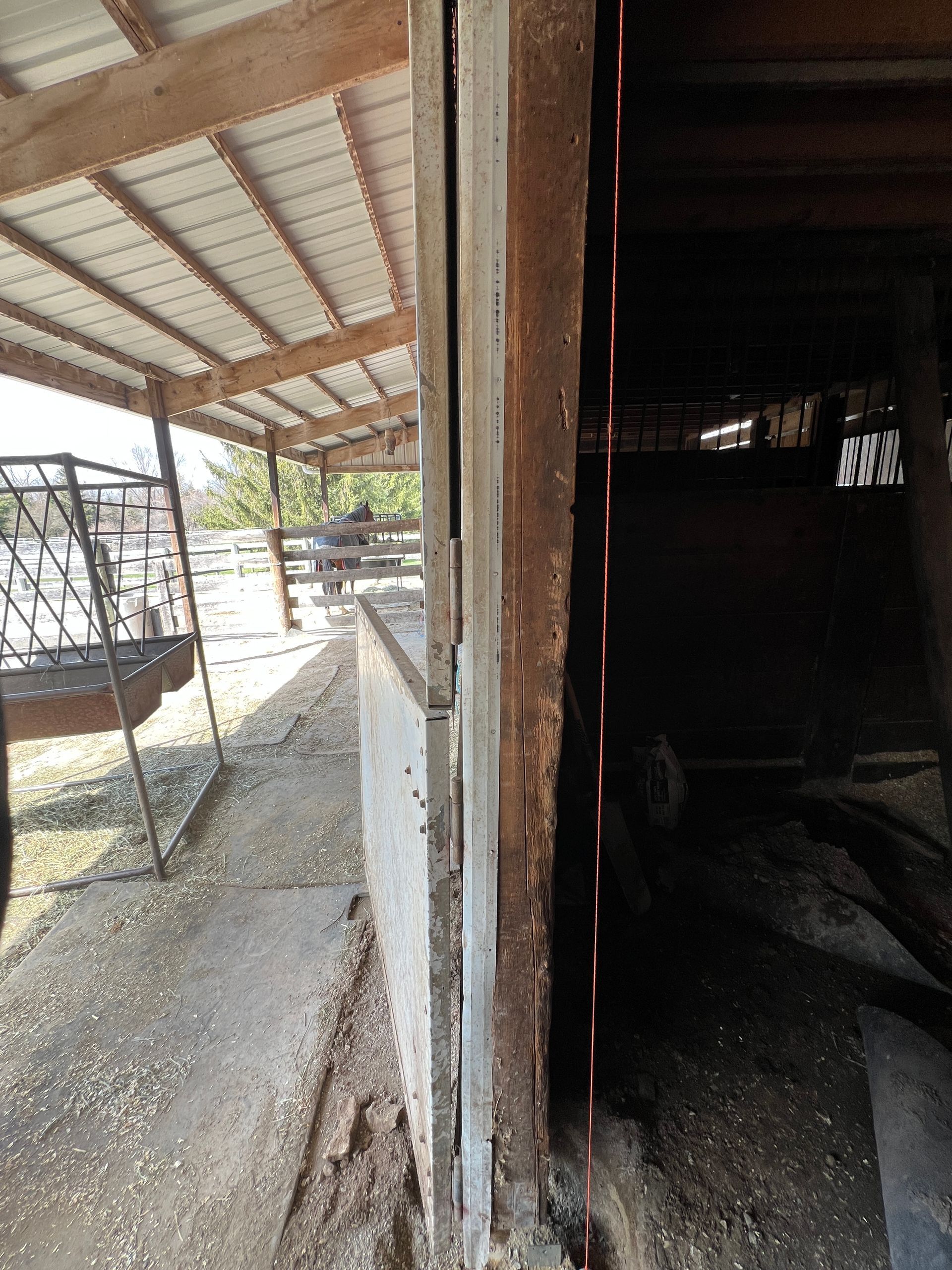 A wooden post on a farm structure shows signs of significant decay and termite damage along its edge.