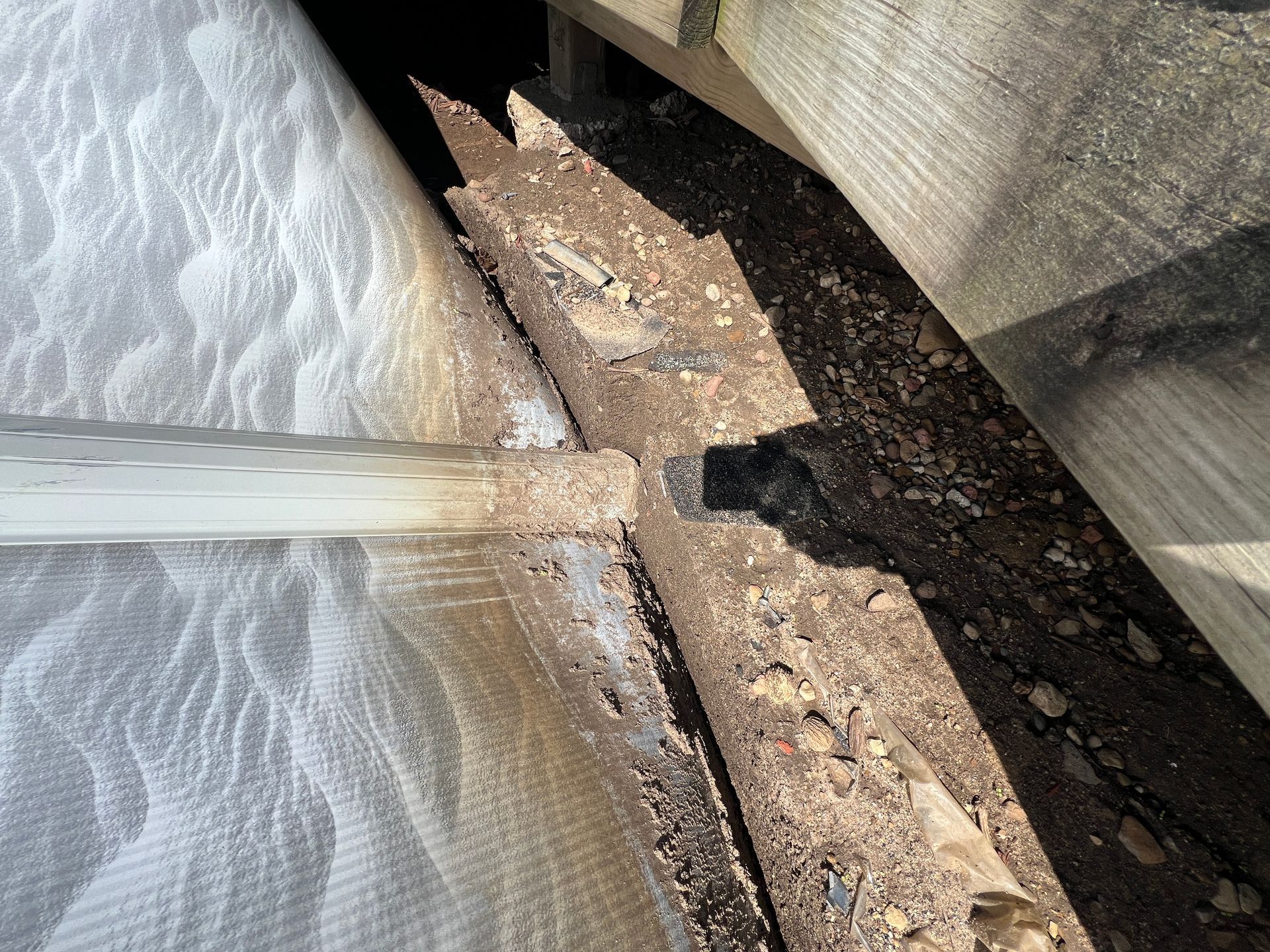 A close-up shot of a broken piece of particle board or decking material with jagged, splintered edges.