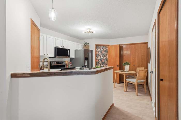 Kitchen with white cabinets, breakfast bar, and small dining area with floral wallpaper.