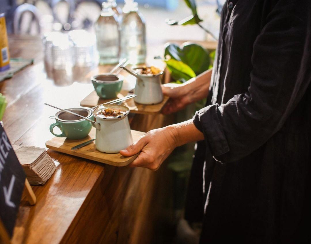 A Woman Is Serving Coffee To A Customer At A Cafe — The Real Grocer In Golden Beach, QLD