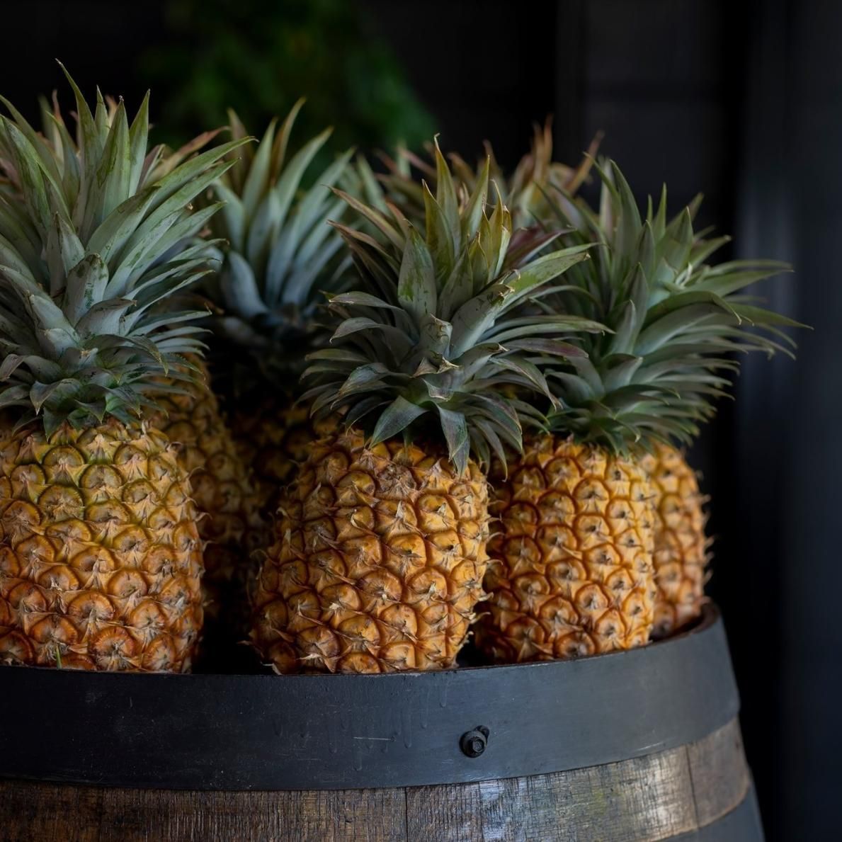 A Bunch Of Pineapples Are Sitting On Top Of A Wooden Barrel — The Real Grocer In Caloundra, QLD