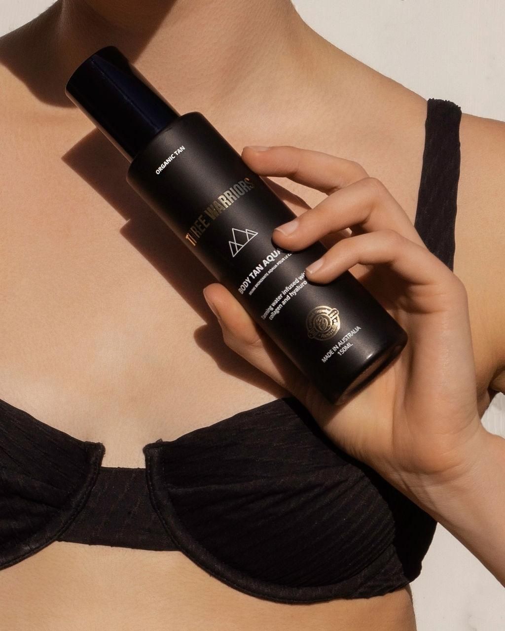 A Woman In A Black Bra Is Holding A Black Bottle — The Real Grocer In Golden Beach, QLD