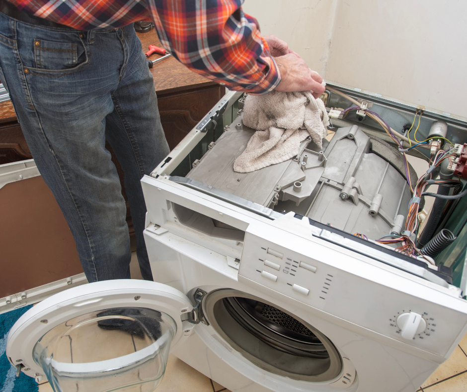Person wiping inside an open dishwasher with the lower rack removed