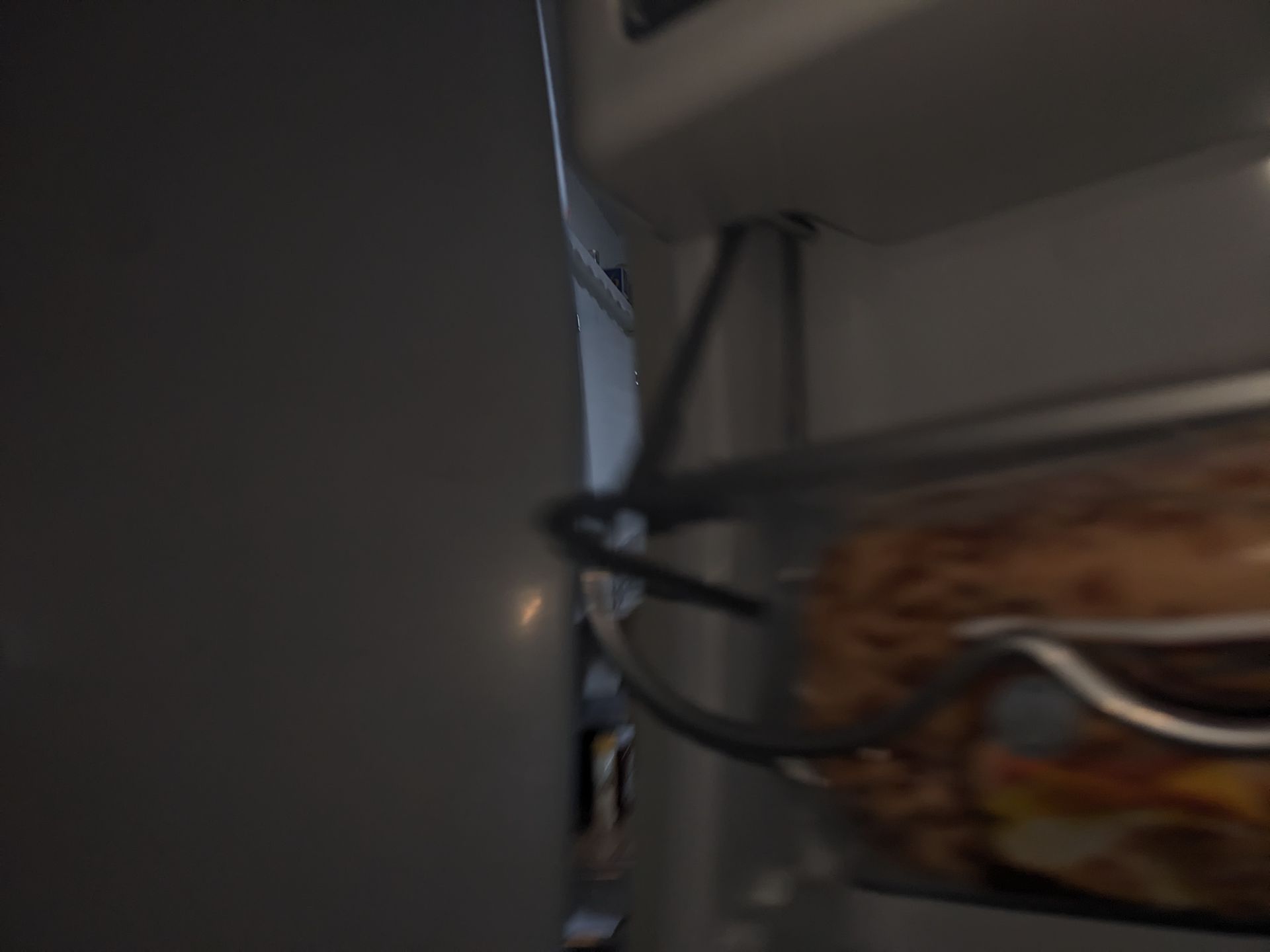 Close-up of tangled black cables beside a wall and a wooden shelf or cabinet