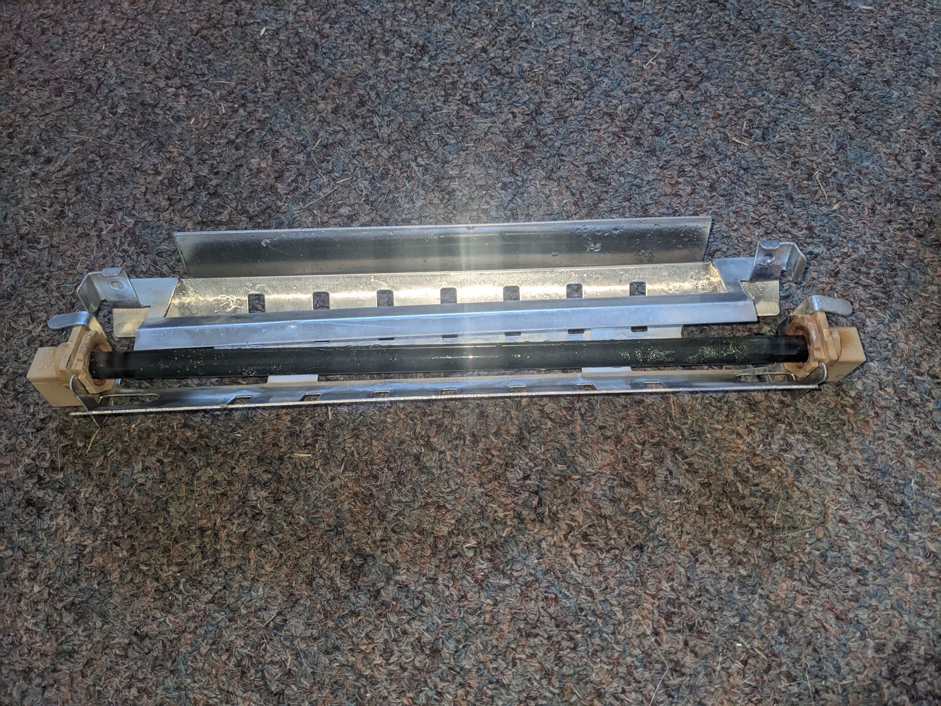 Long metal fluorescent light fixture on a speckled carpeted floor
