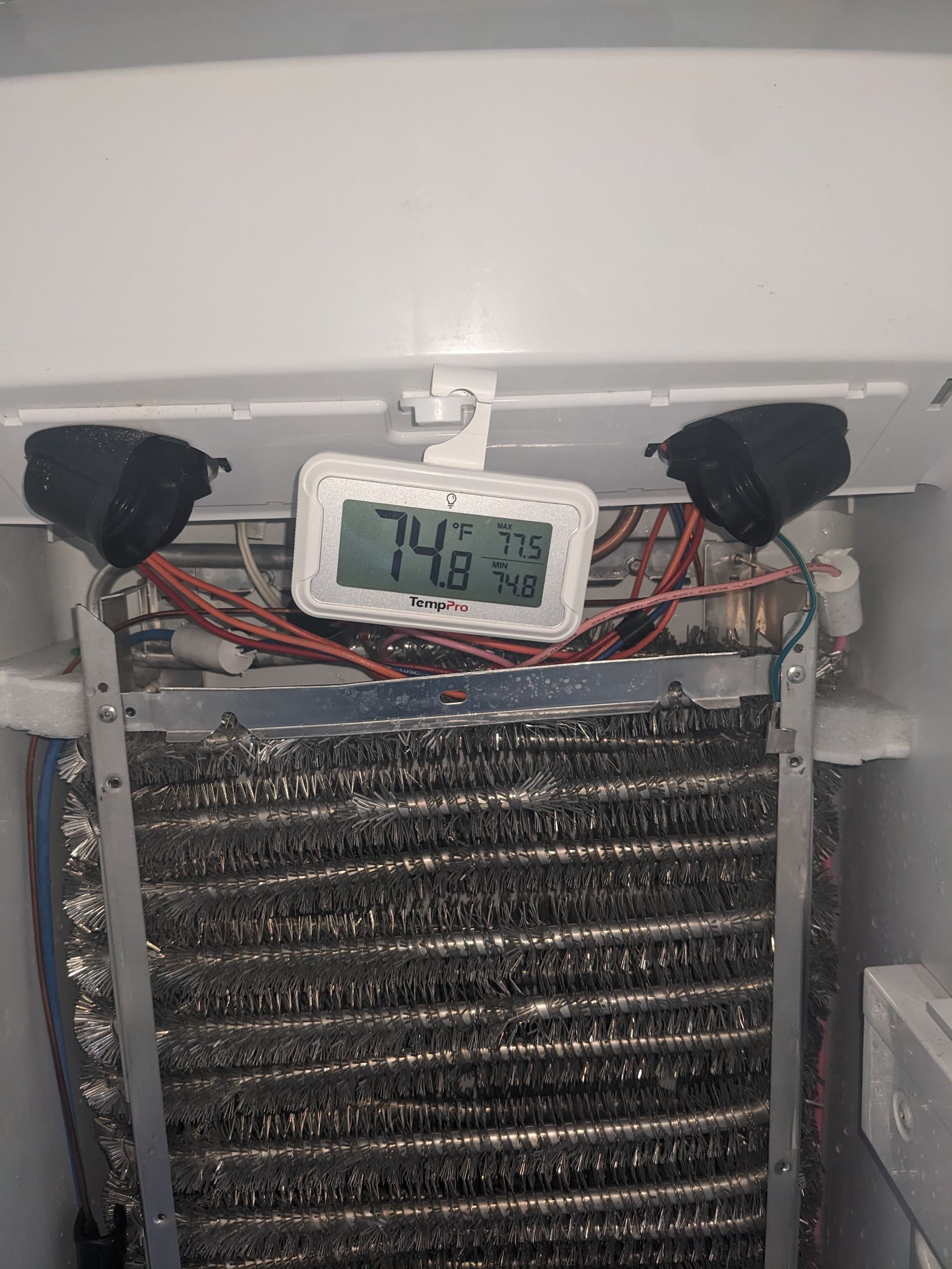 Digital thermometer on a metal heat exchanger shows 74.8°F, with wires and fan mounted above.