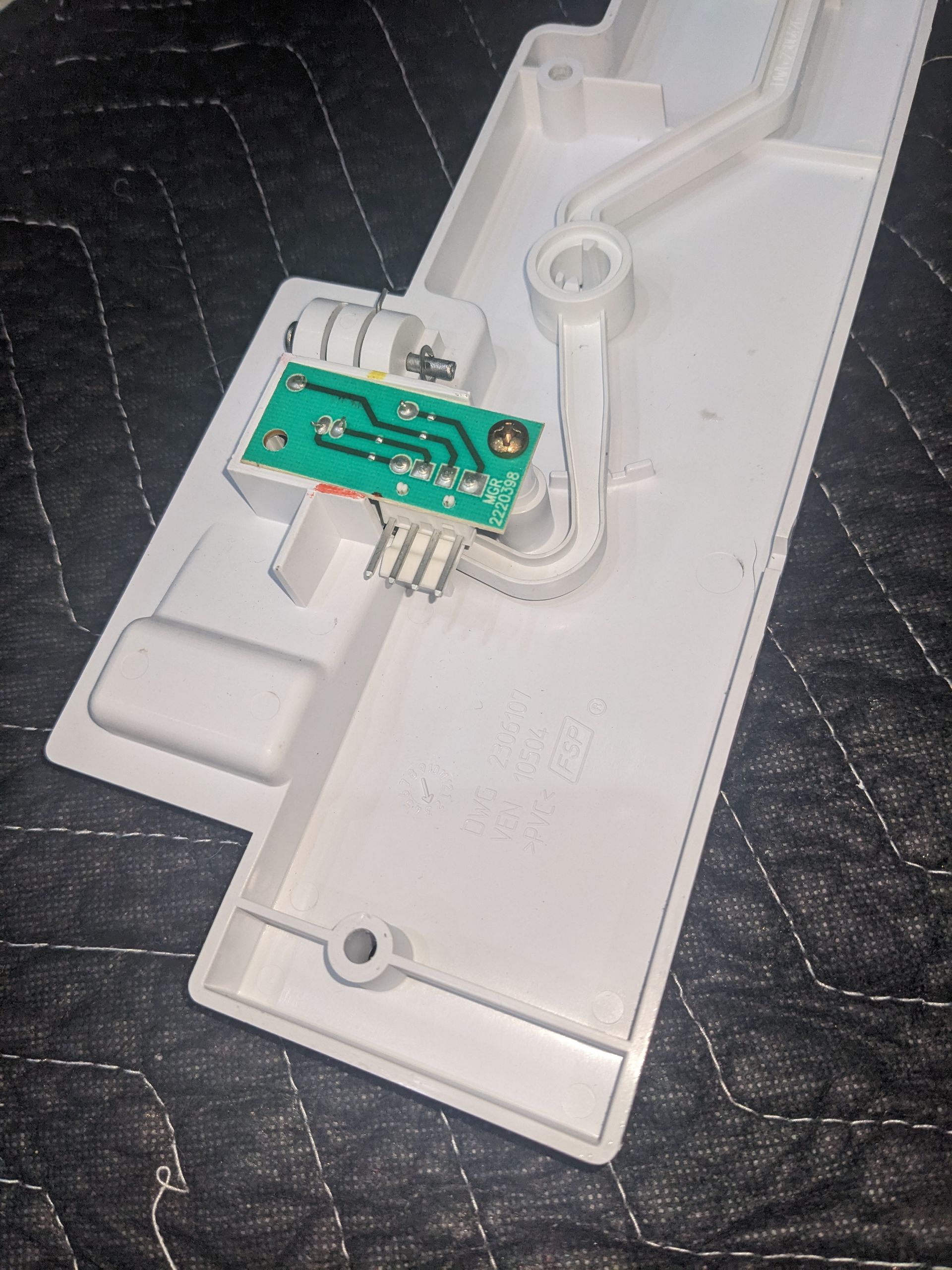 White plastic device housing with a small green circuit board and wires inside.