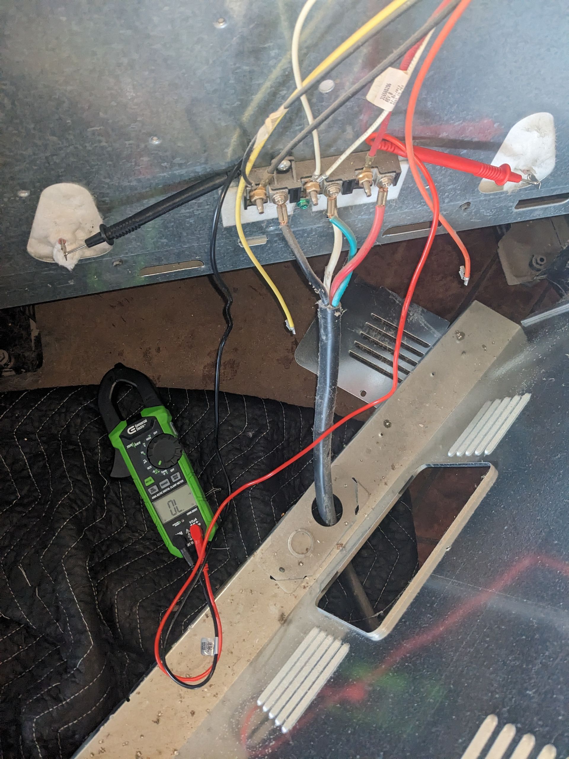 Exposed wiring and tools inside a floor opening, with red and black wires connected to a junction.