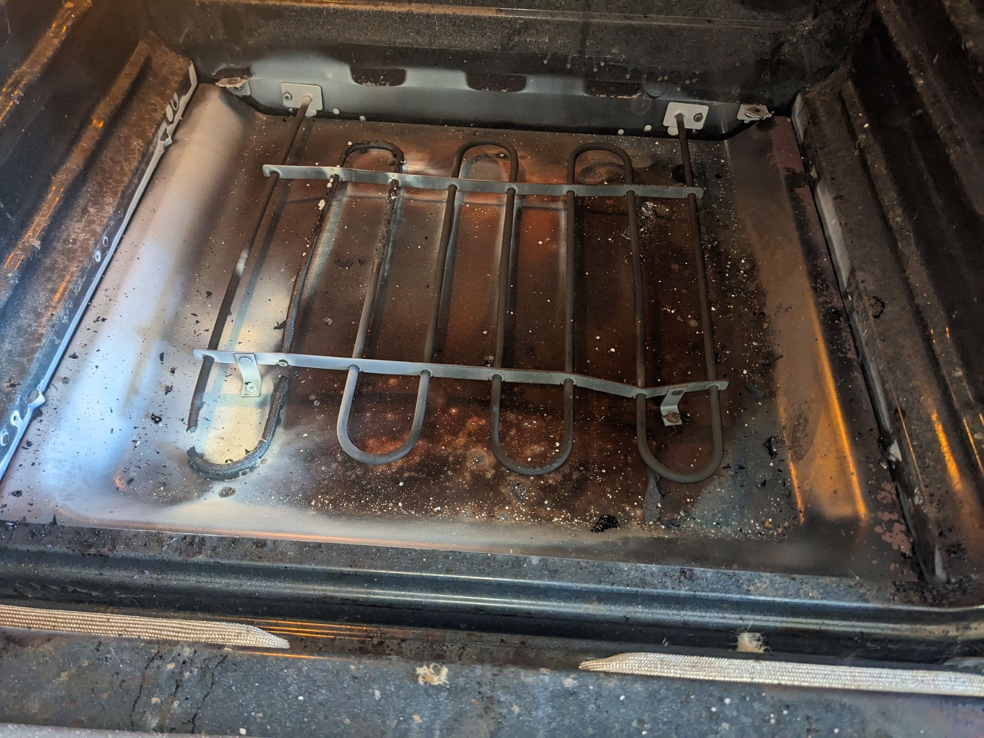 Dirty oven interior with a metal heating element and dark grime buildup