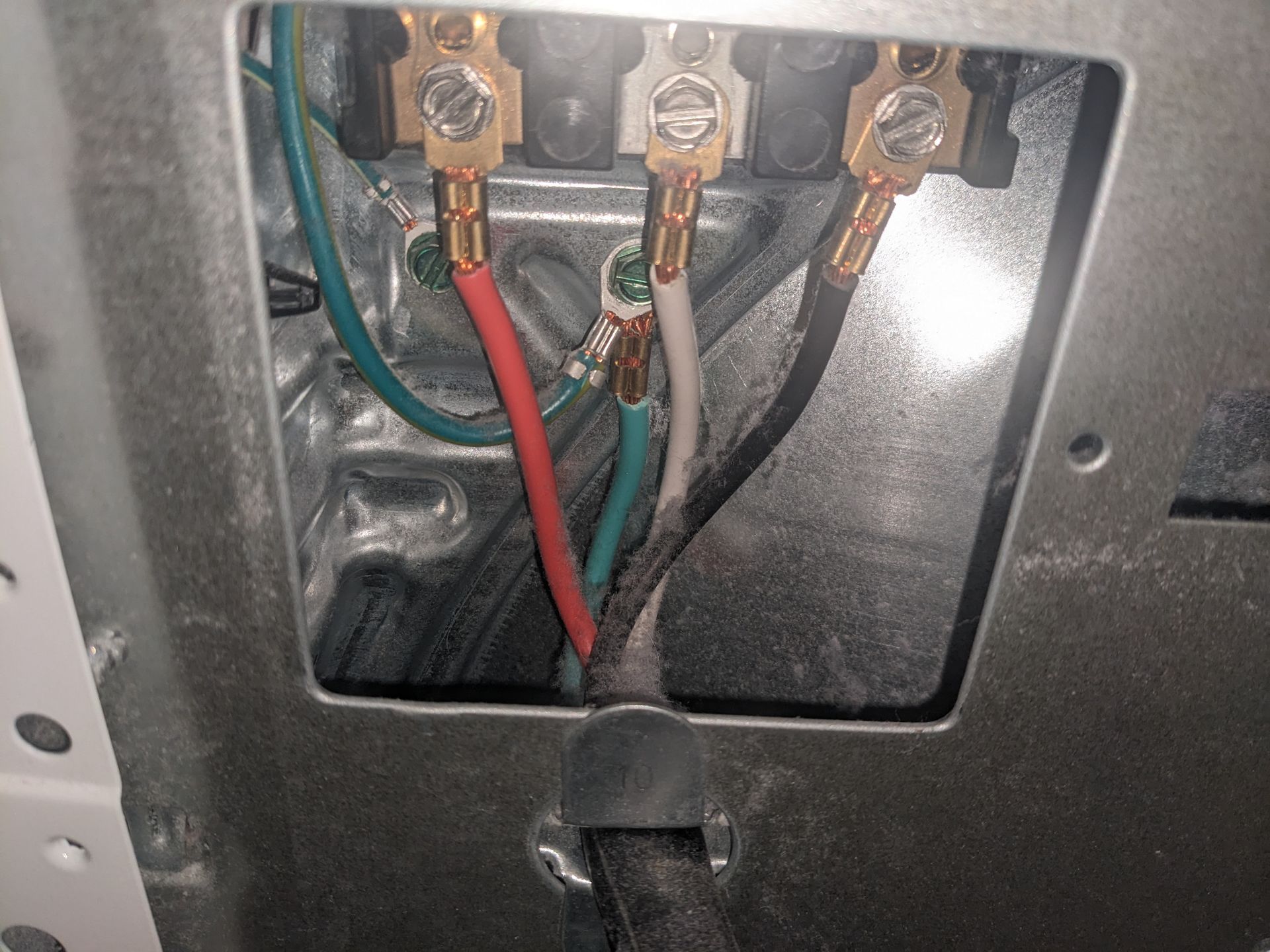 Electrical wiring and terminals inside a metal panel box, with red and green wires connected to brass lugs.