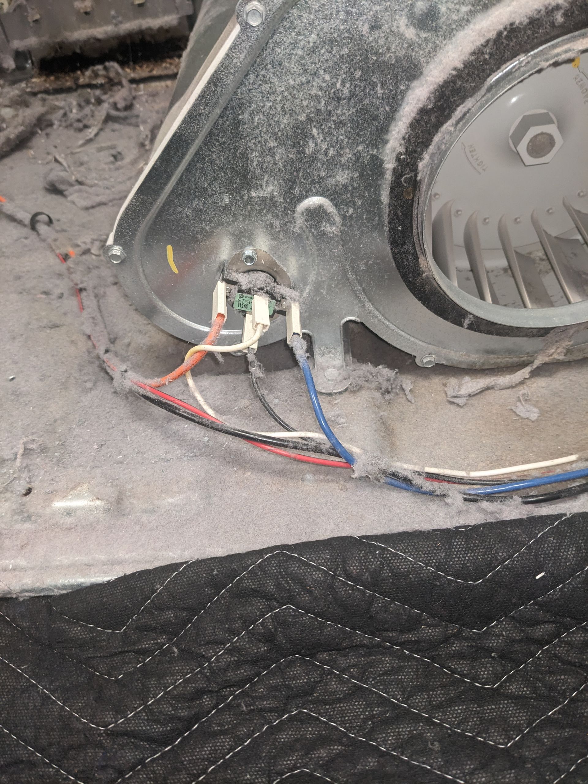 Close-up of dusty machinery wiring with red, blue, and green cables connected to a motor housing
