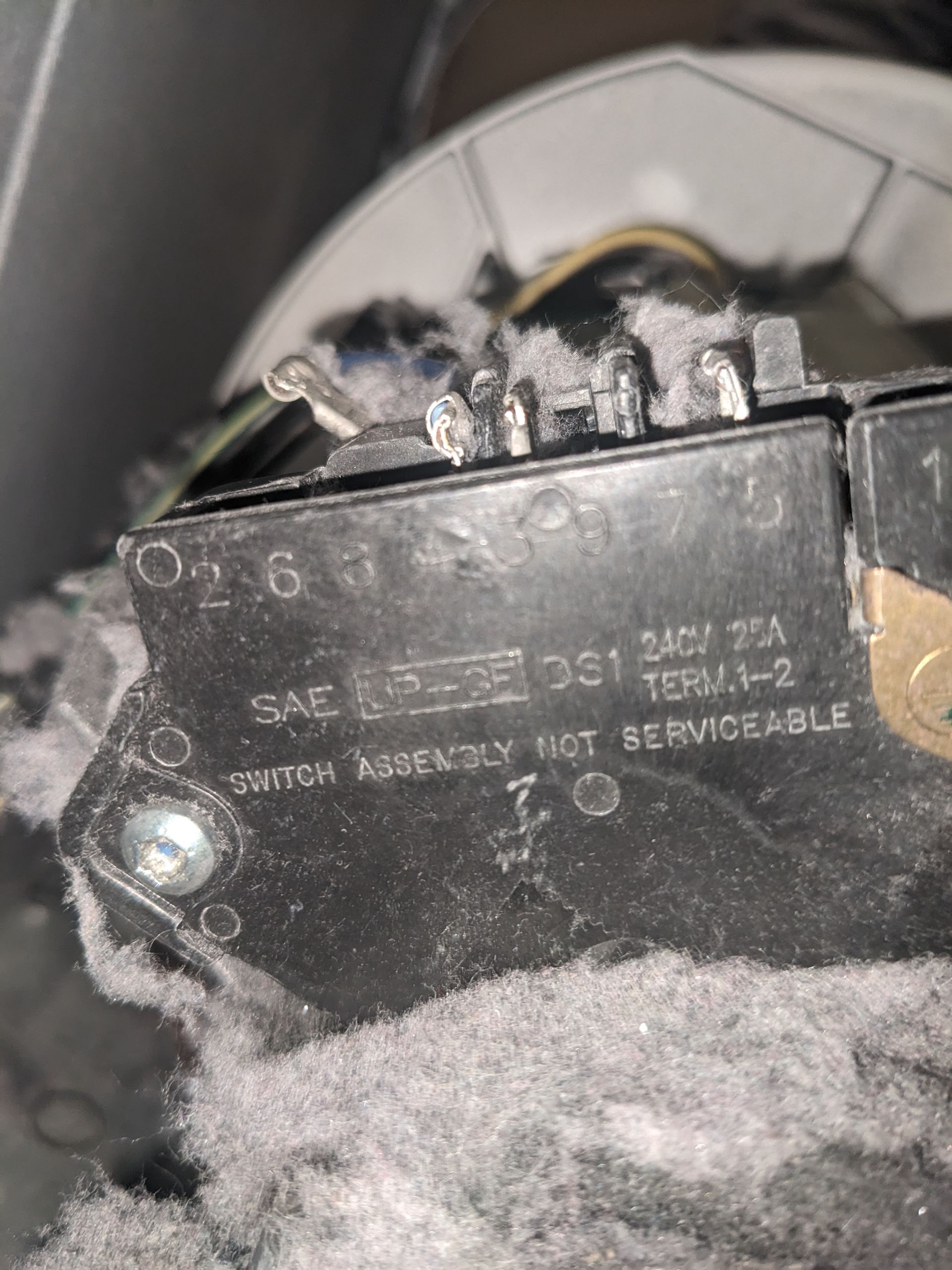 Close-up of a black electronic device label with wiring and dusty surroundings