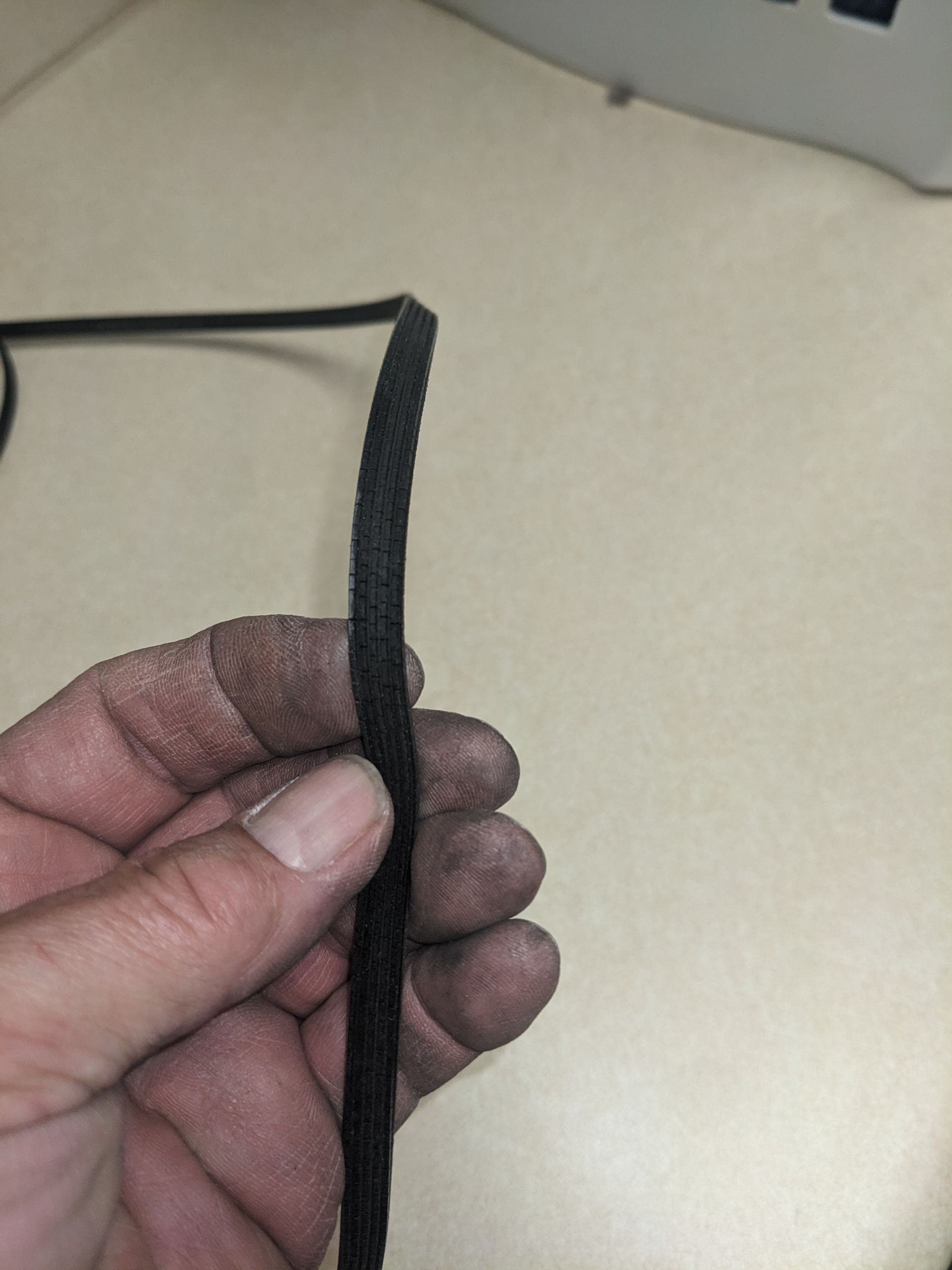 Hand holding a black woven strap against a light-colored background
