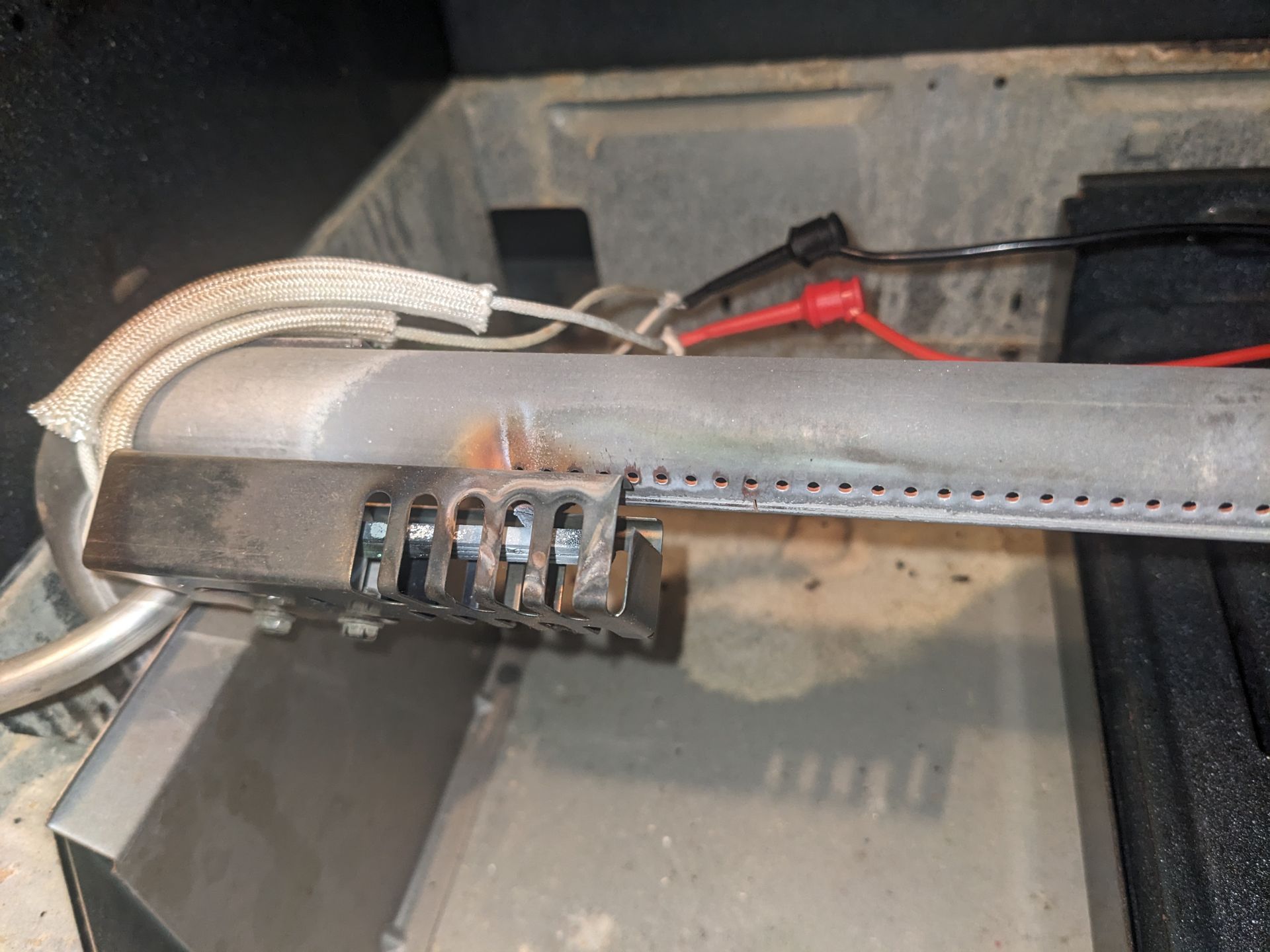 Close-up of a damaged electrical wire connector with exposed wires inside a metal panel