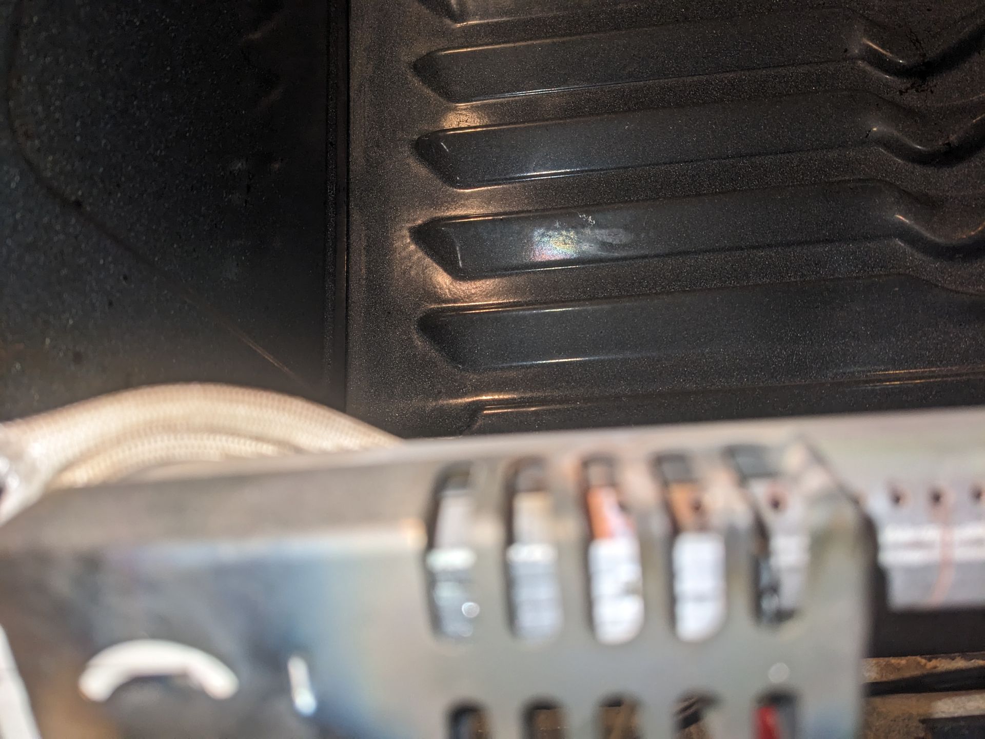 Close-up of a metal device with slotted vents and blurred dials beside a black textured surface