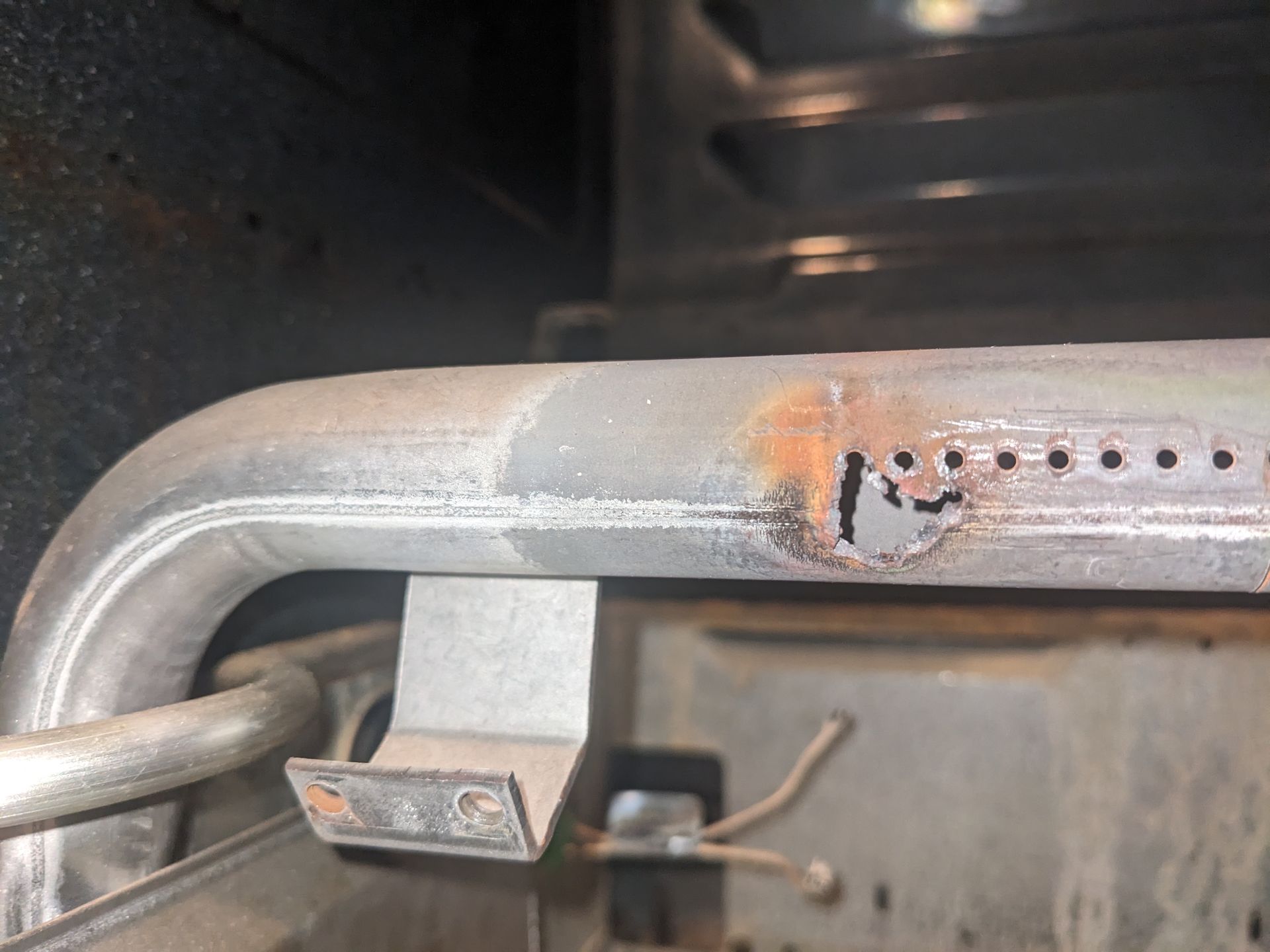 Rusty metal railing with chipped paint and a small bracket in a workshop-like setting