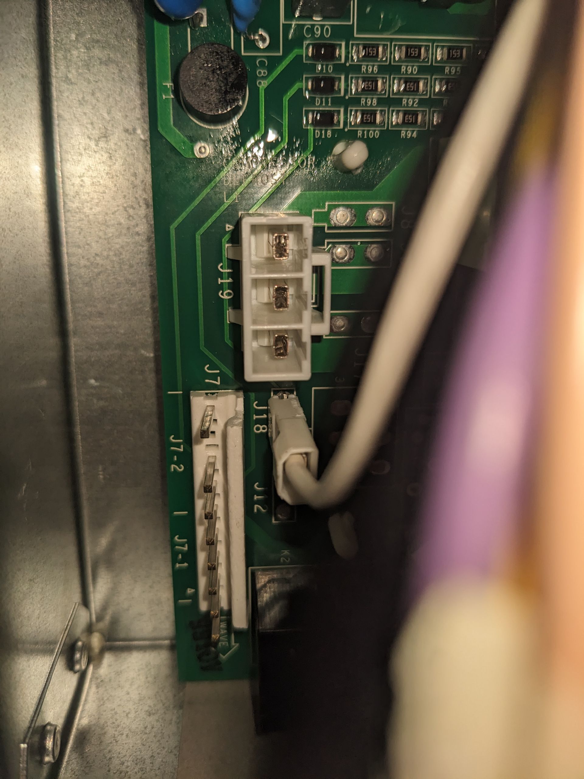 Close-up of a circuit board with white connectors and bundled wires inside a device case