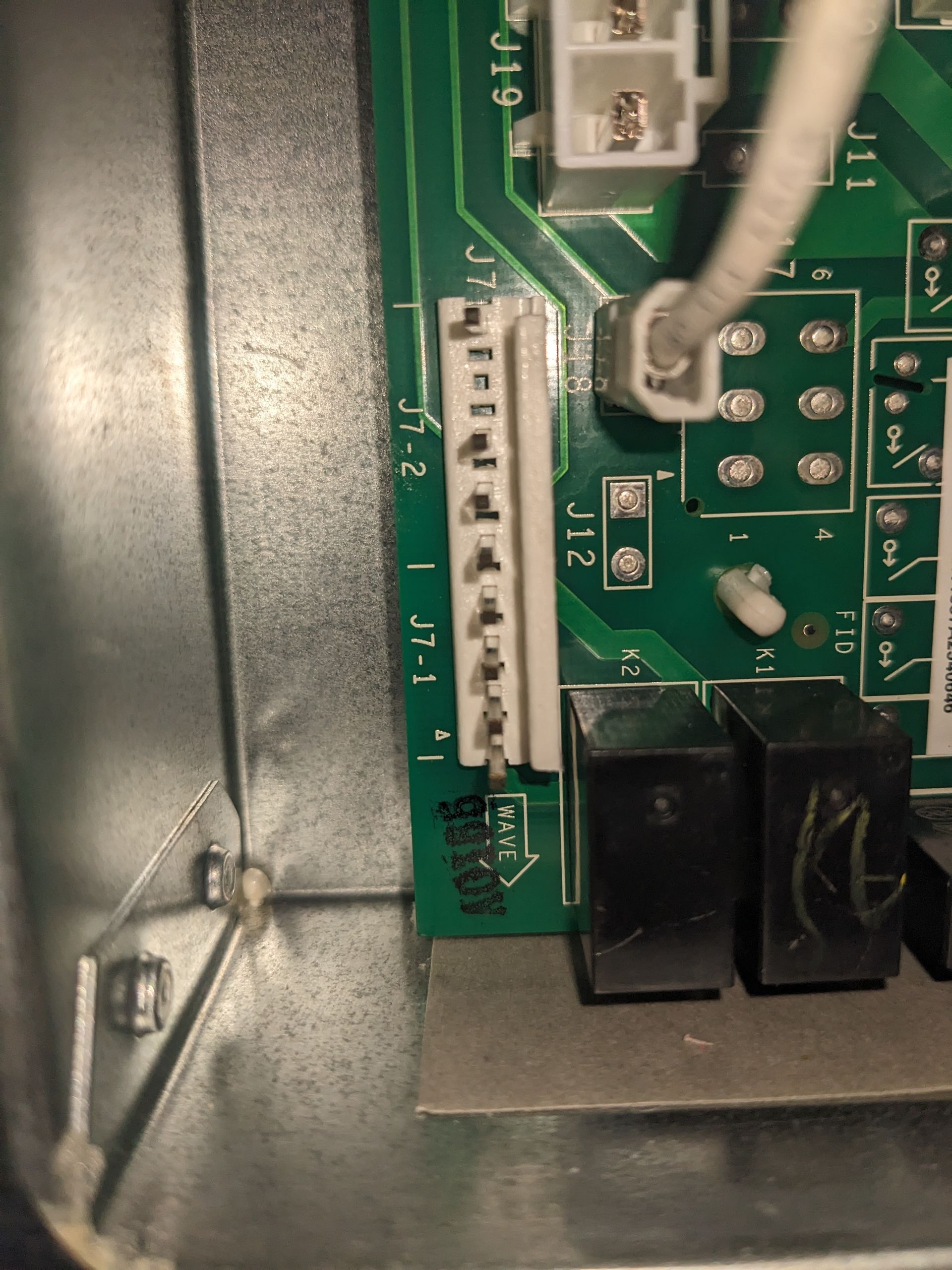 Close-up of a circuit board with white connectors and attached gray and white wires.