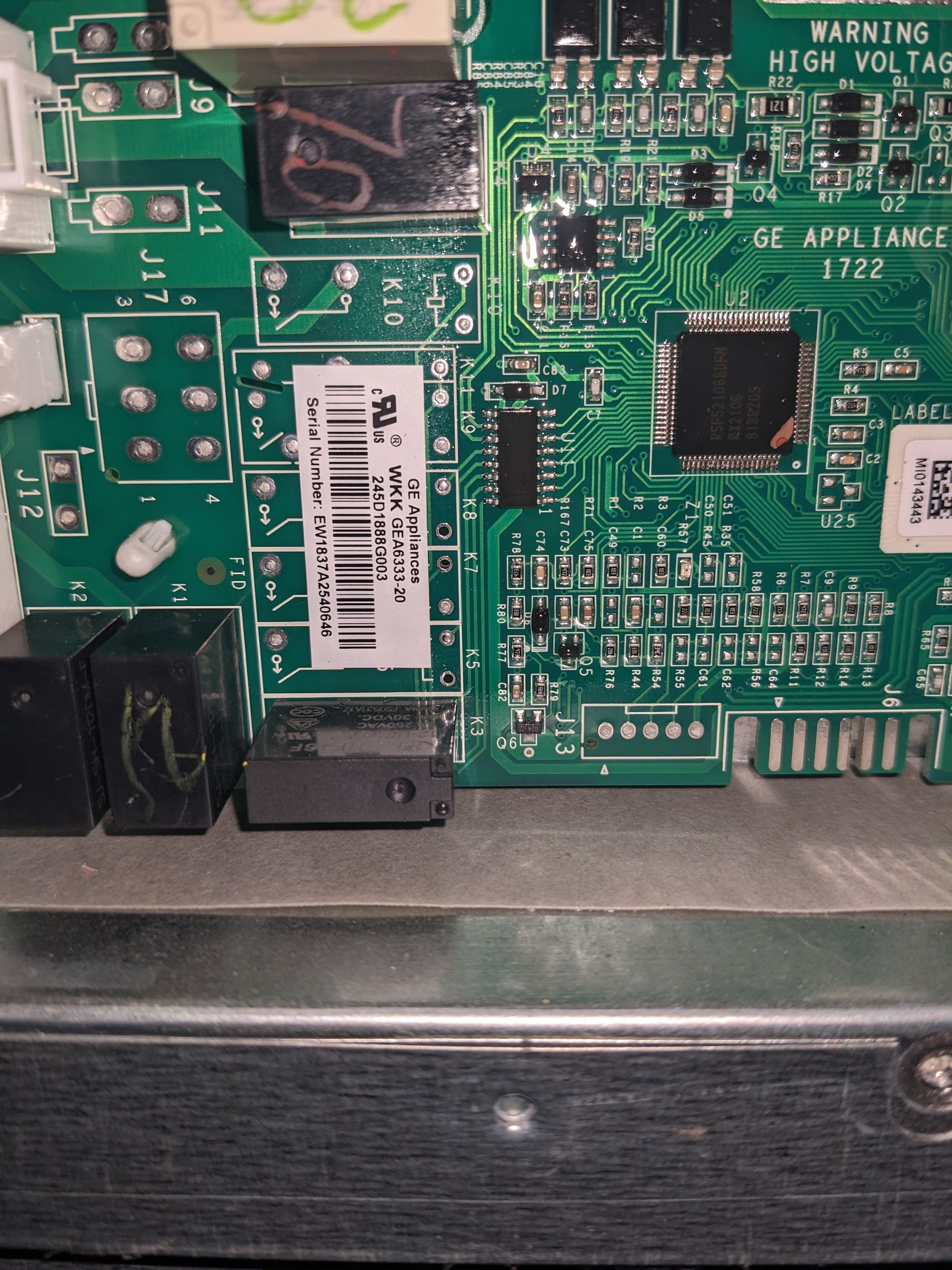 Close-up of a green circuit board with chips, connectors, and a barcode label inside electronic equipment