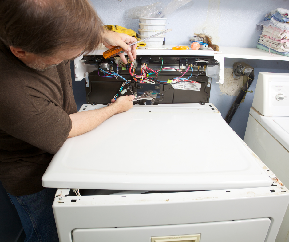 Person repairing wiring inside a washing machine in a laundry room