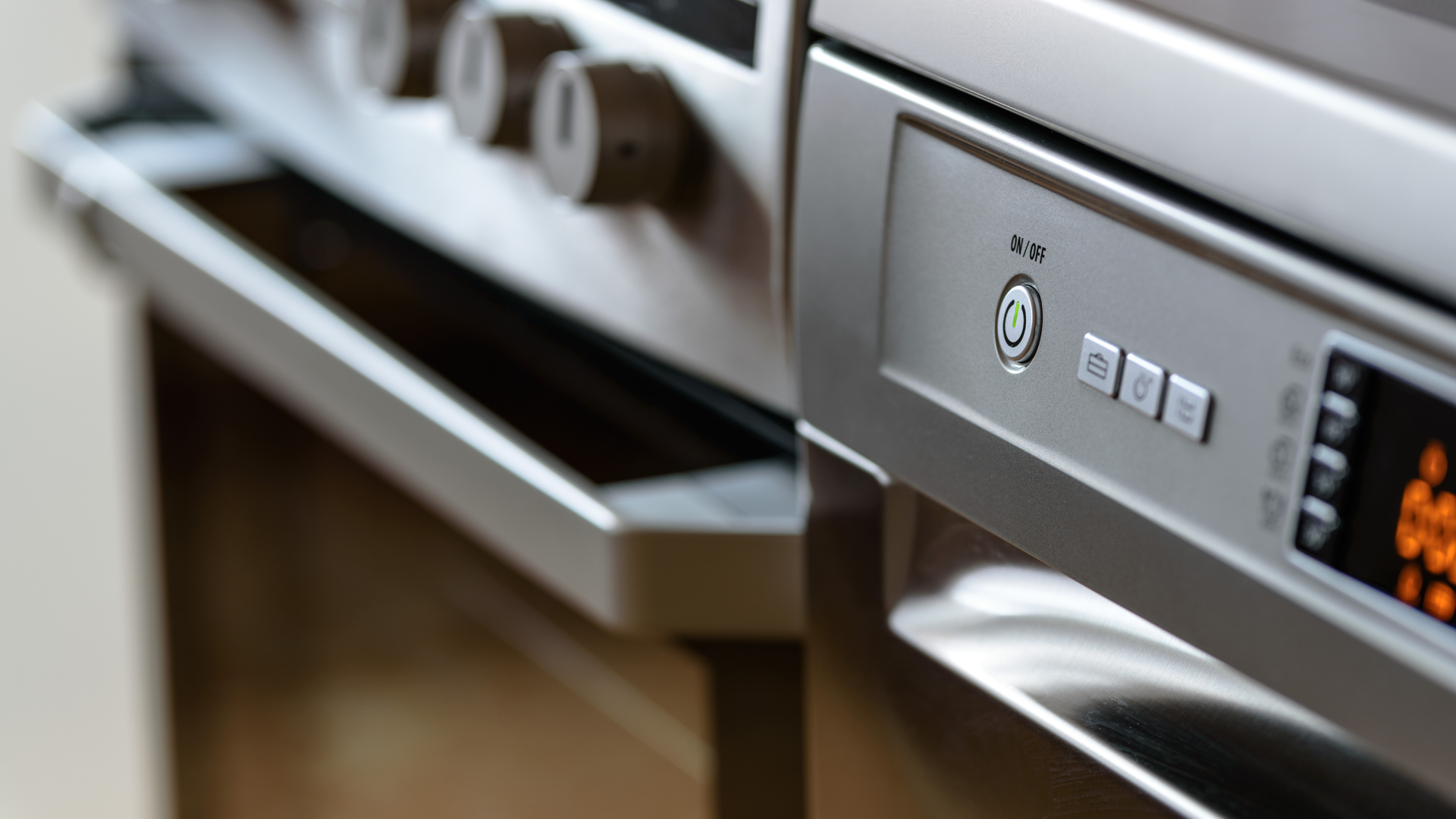 Close-up of a stainless steel kitchen oven with control knobs and digital display