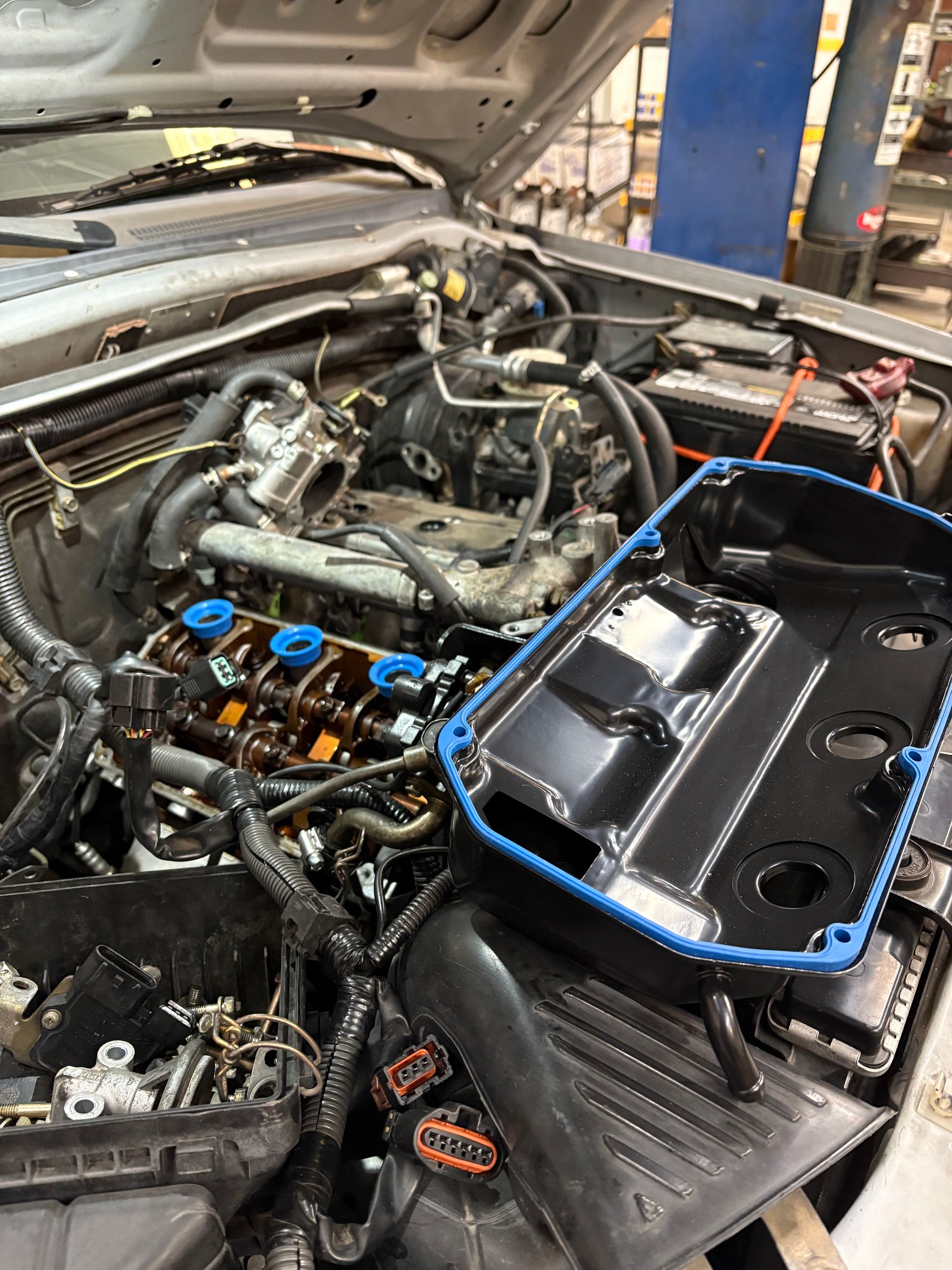 The image displays an open engine bay with a removed valve cover, which is a common sight during automotive maintenance or repair, such as a knock sensor harness replacement job.