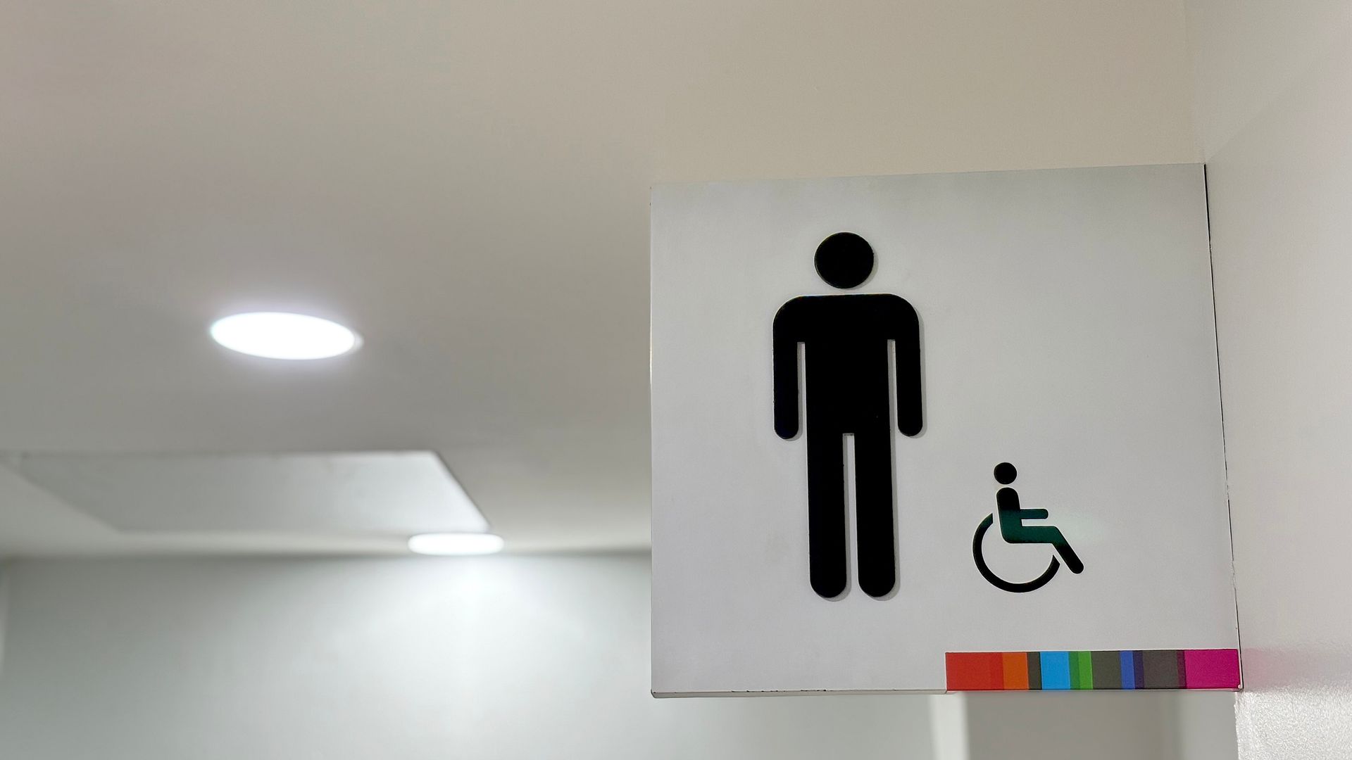 Restroom sign displaying standard and wheelchair accessibility symbols mounted in a clean hallway. Restroom sign displaying standard and wheelchair accessibility symbols mounted in a clean hallway.
