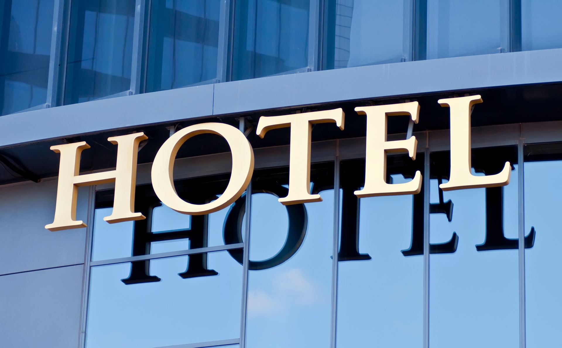 A gold hotel sign mounted on a modern glass building exterior. A gold hotel sign mounted on a modern glass building exterior.
