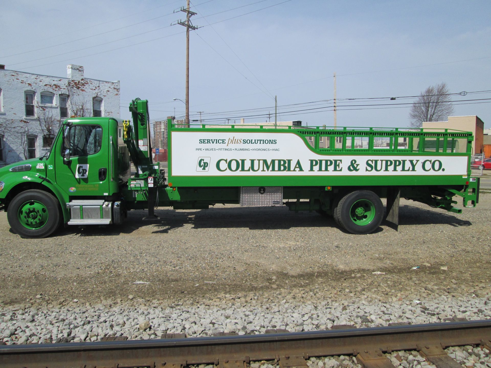 Green Columbia Pipe & Supply truck parked next to railroad tracks.