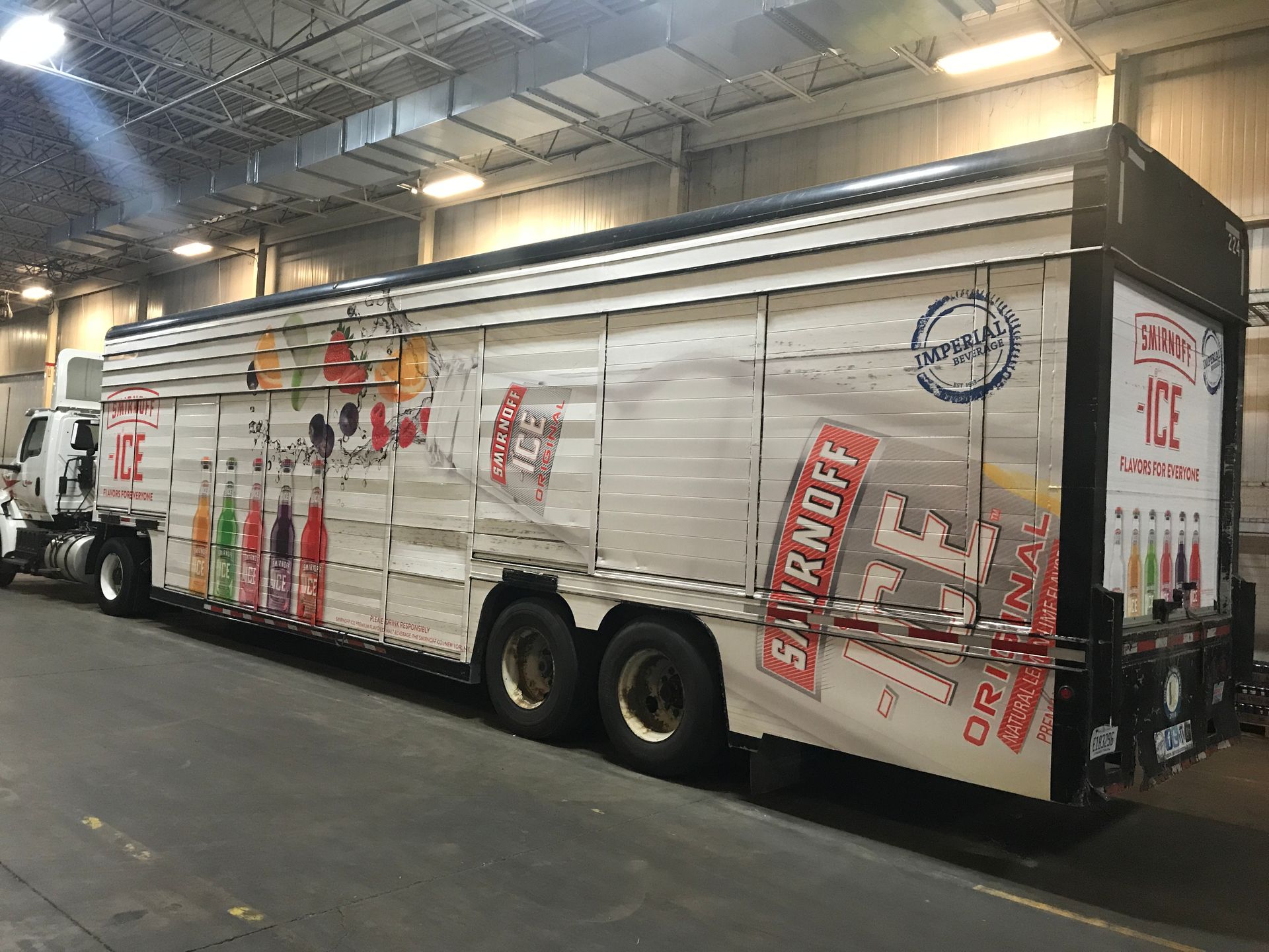 Smirnoff Ice branded semi-truck in a warehouse. White trailer with colorful drink graphics and logo.