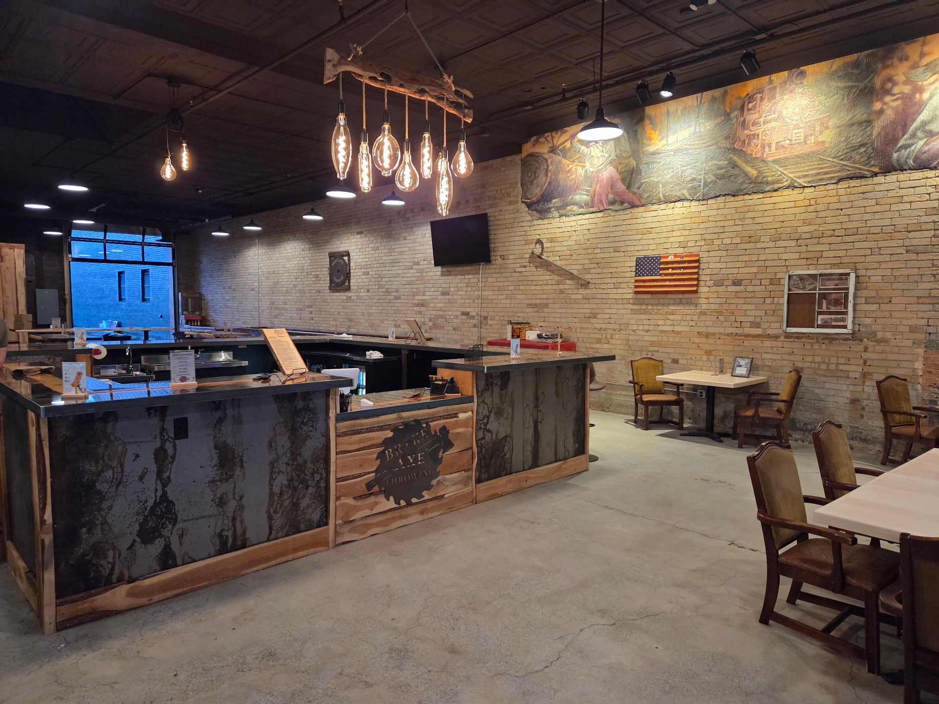 Group posing in a wooden indoor arena with a U.S. flag on the wall behind them.
