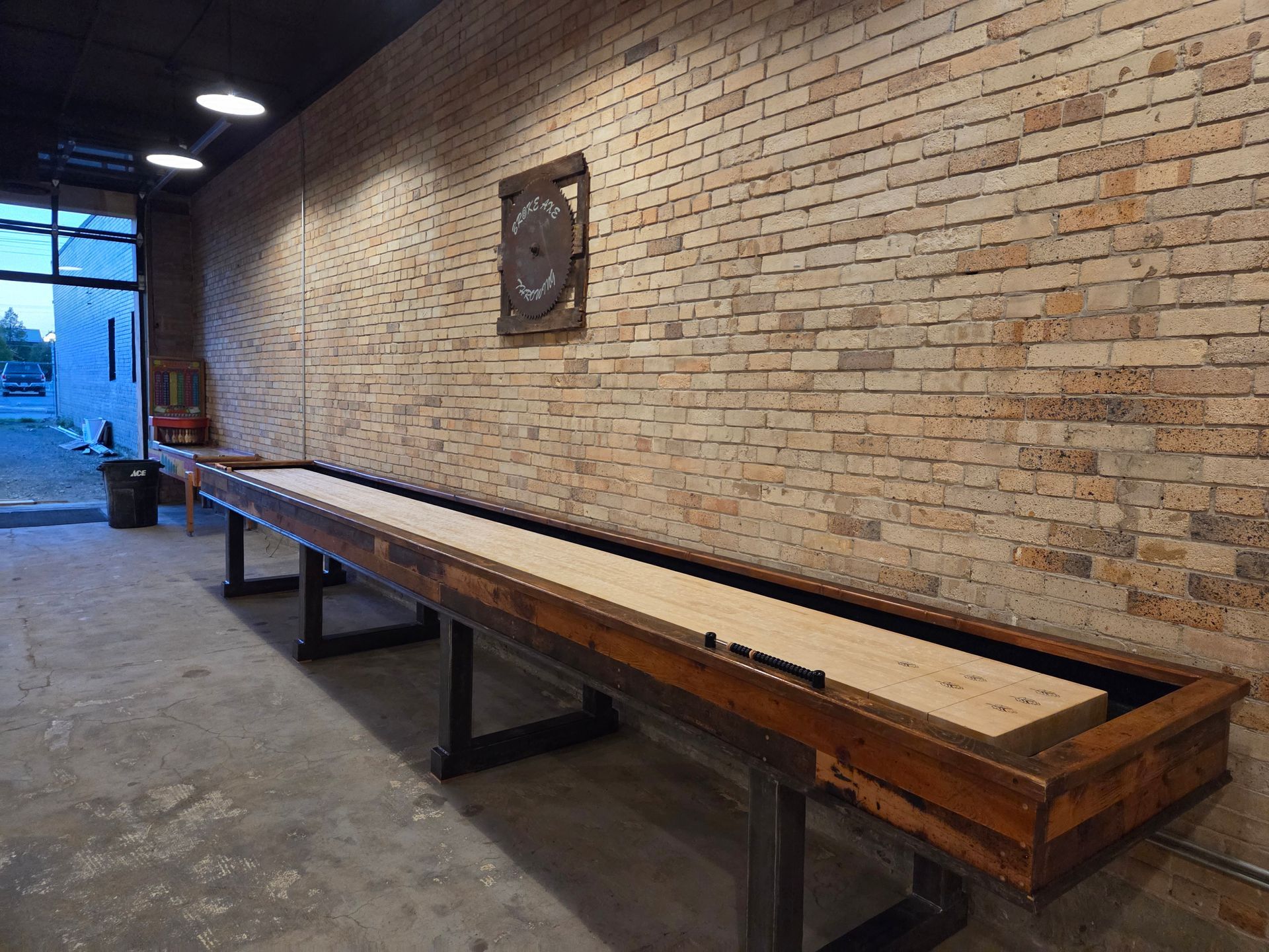 Two people standing at an axe-throwing lane with wooden targets and a log-lined backdrop