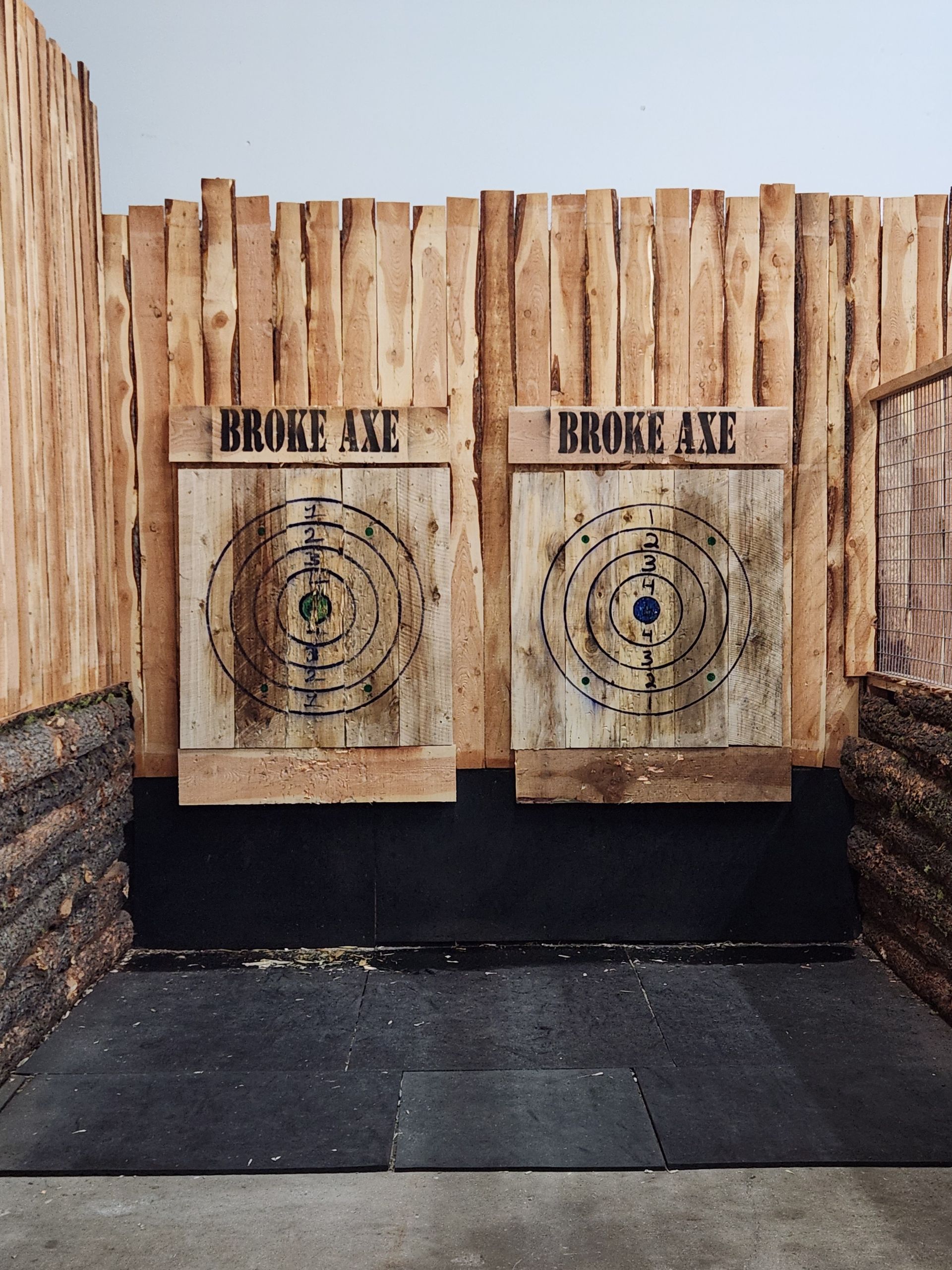 Two axe-throwing targets against a wood fence in a rustic outdoor lane