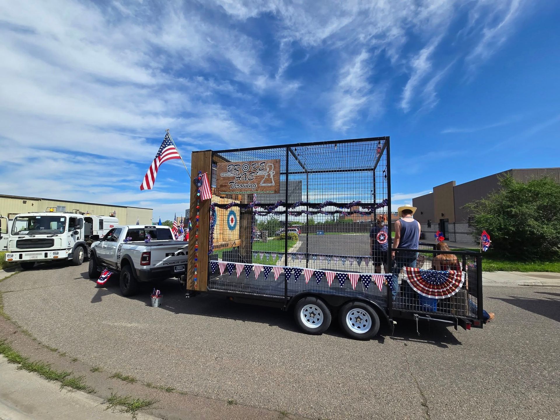 Patriotic float trailer with American flags and bunting parked at an outdoor event under a blue sky