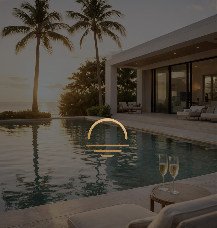 Luxury beachfront villa with infinity pool at sunset, palm trees, and two champagne glasses on a lounge chair