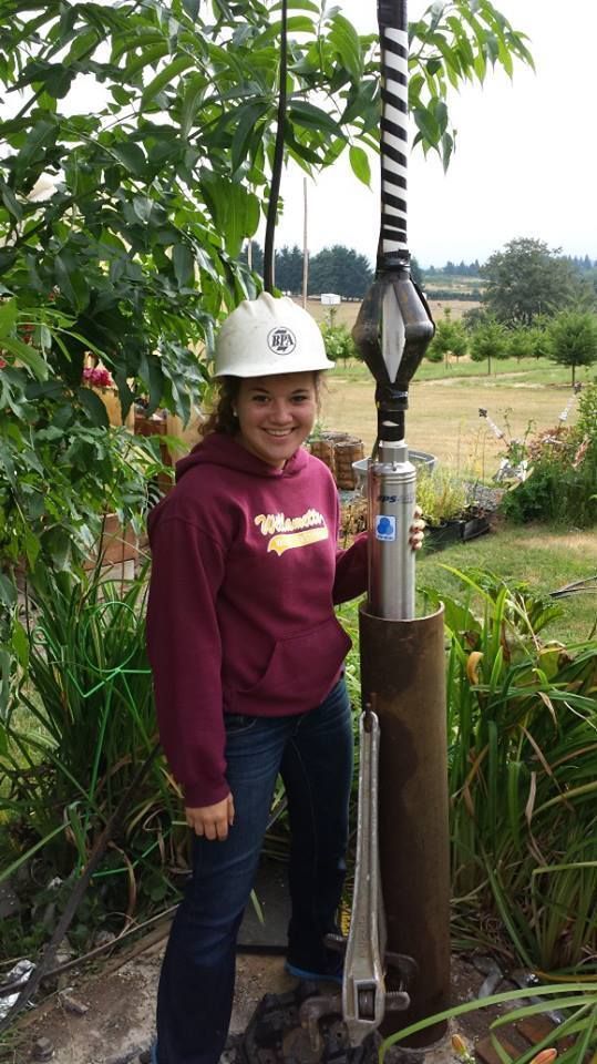 Woman in hard hat holding a drilling tool in a garden. Woman in hard hat holding a drilling tool in a garden.