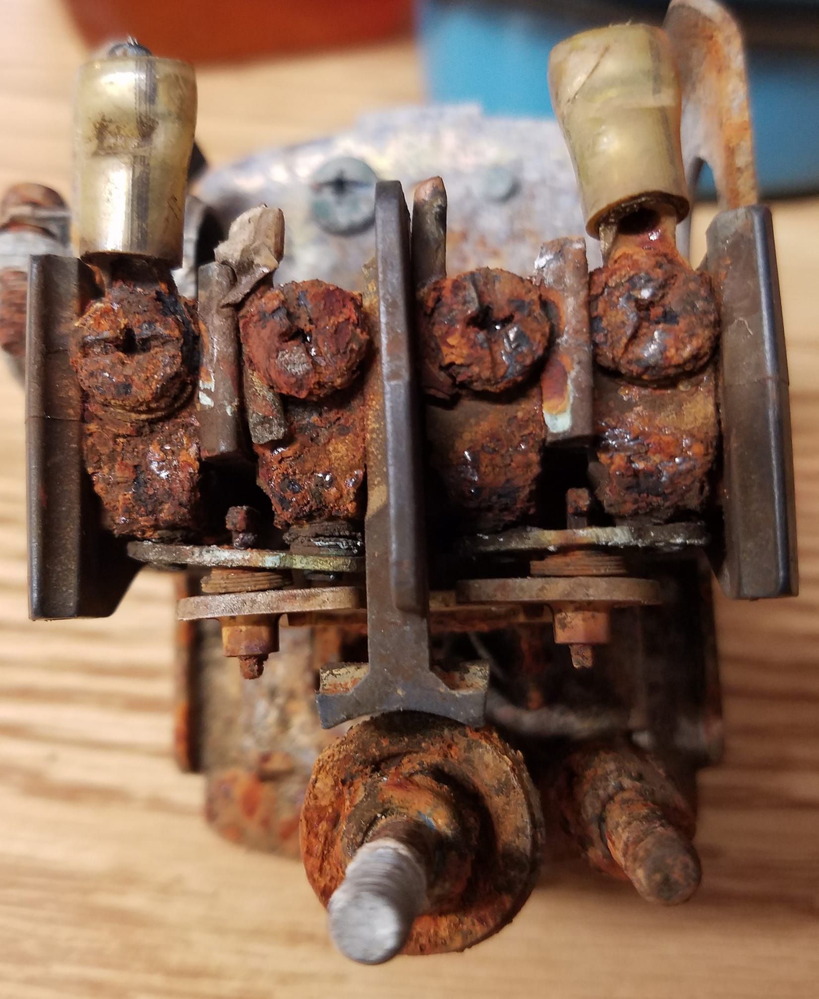 Heavily corroded electrical component with brass connectors, rusted screws, and metal parts. Heavily corroded electrical component with brass connectors, rusted screws, and metal parts.