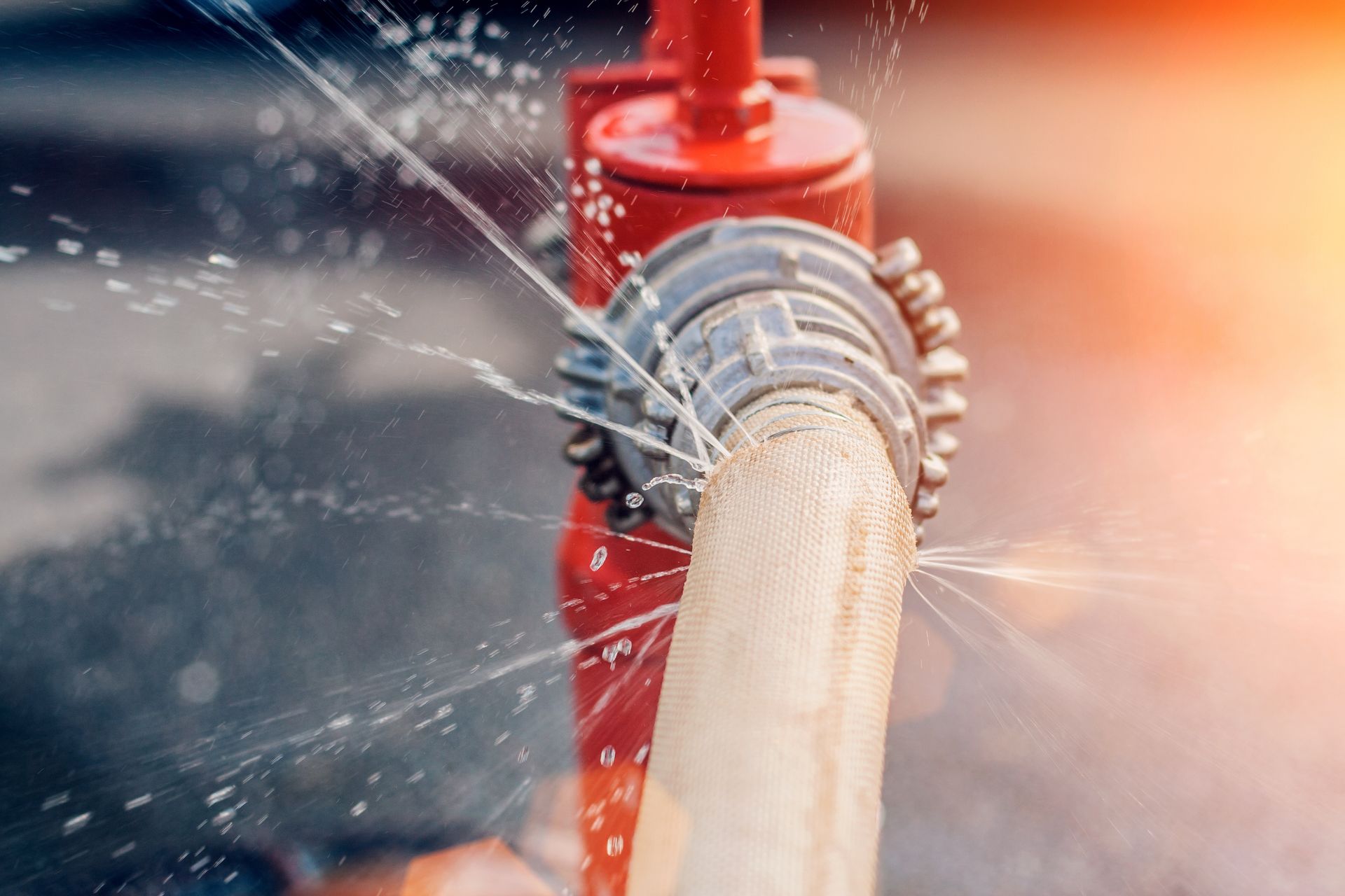 Red fire hydrant with a leaking hose, water spraying. Red fire hydrant with a leaking hose, water spraying.