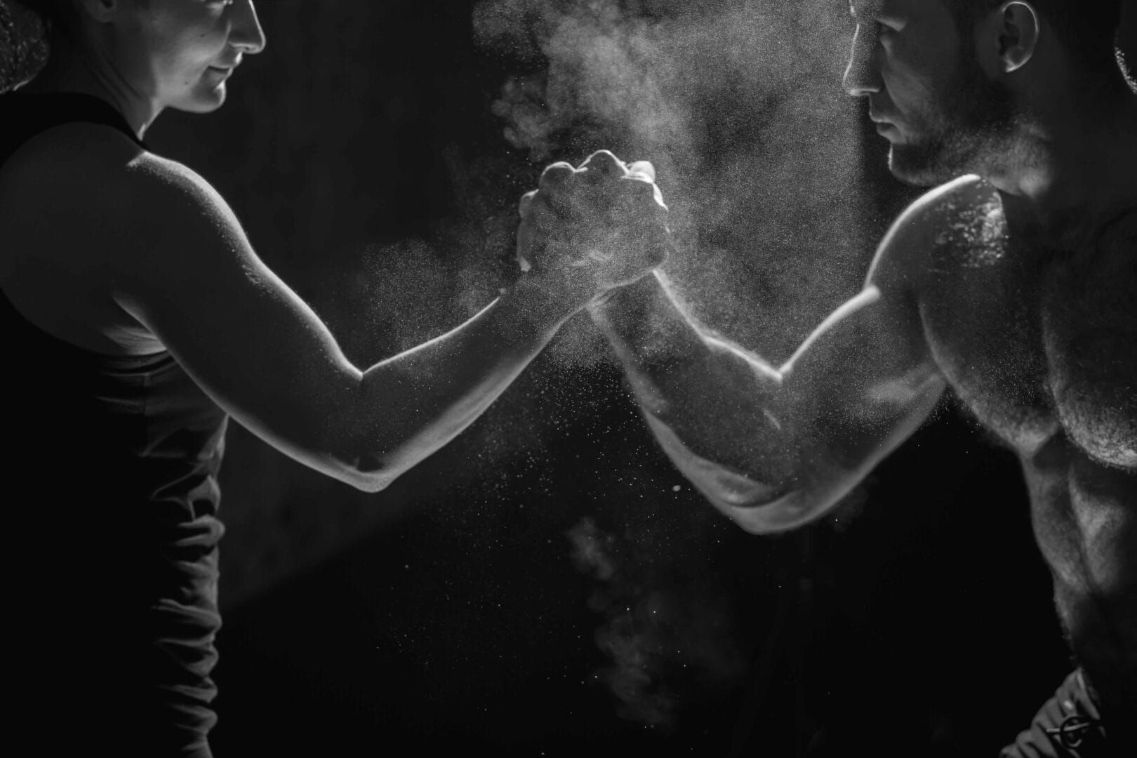 A man and a woman are arm wrestling in a gym.