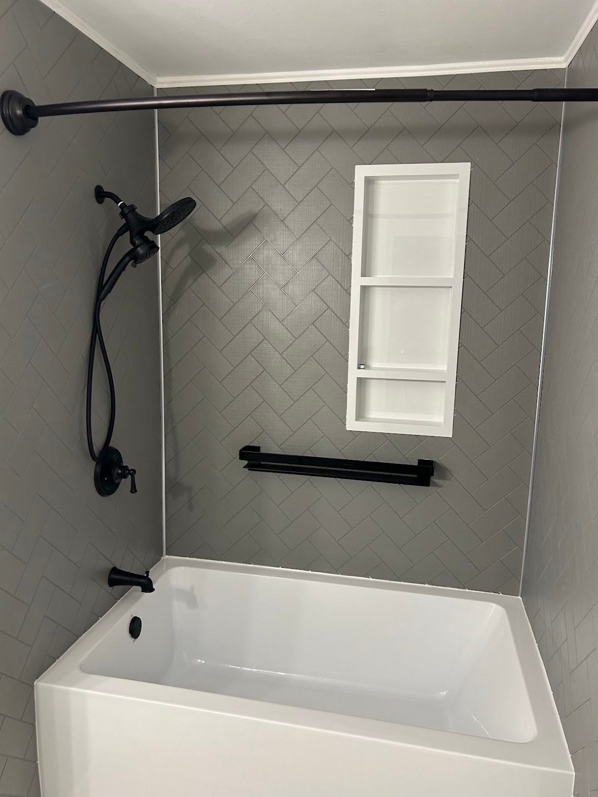 A bathroom with a bathtub , shower , and shelf.