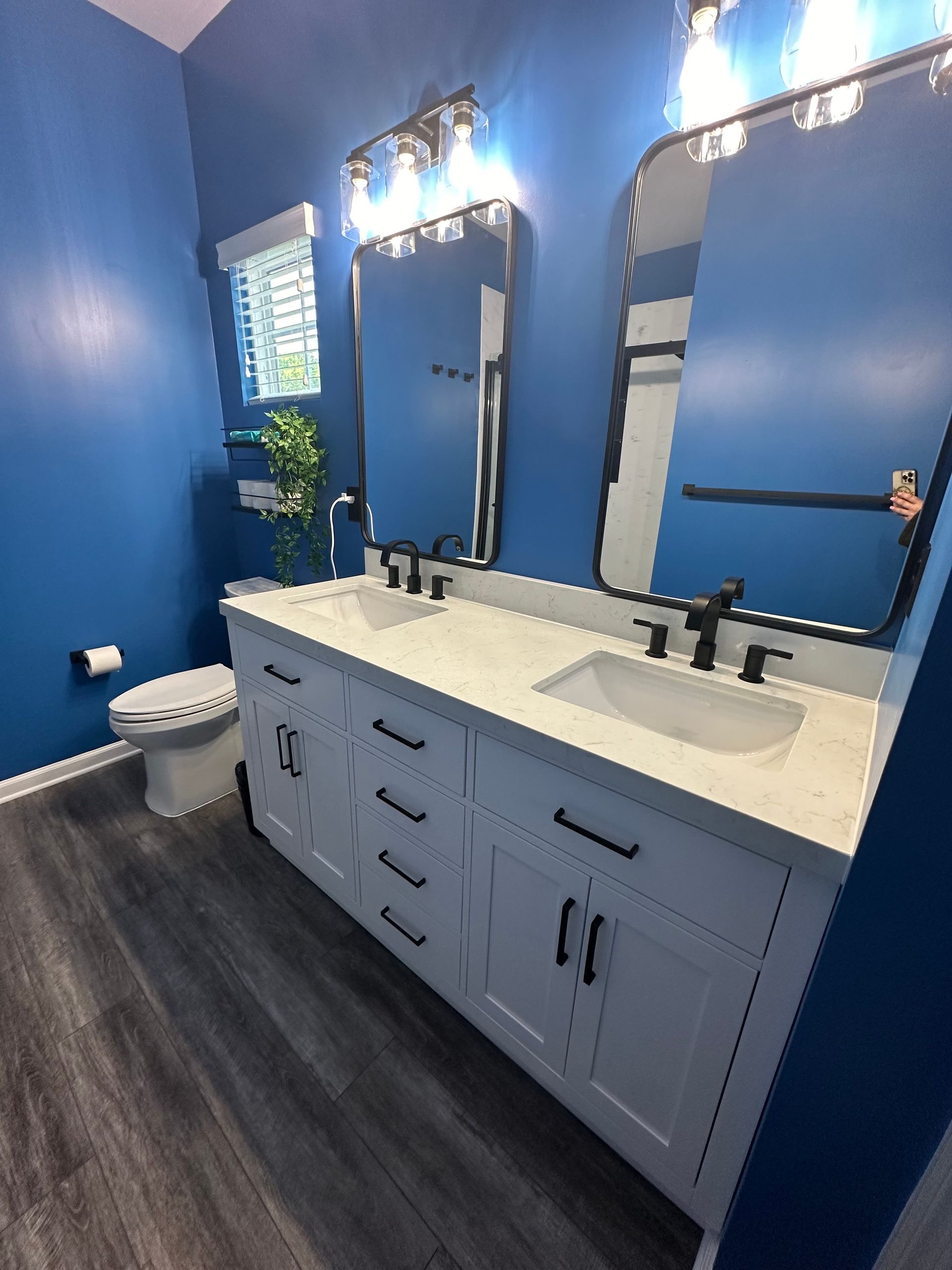 A bathroom with two sinks , a toilet , and two mirrors.