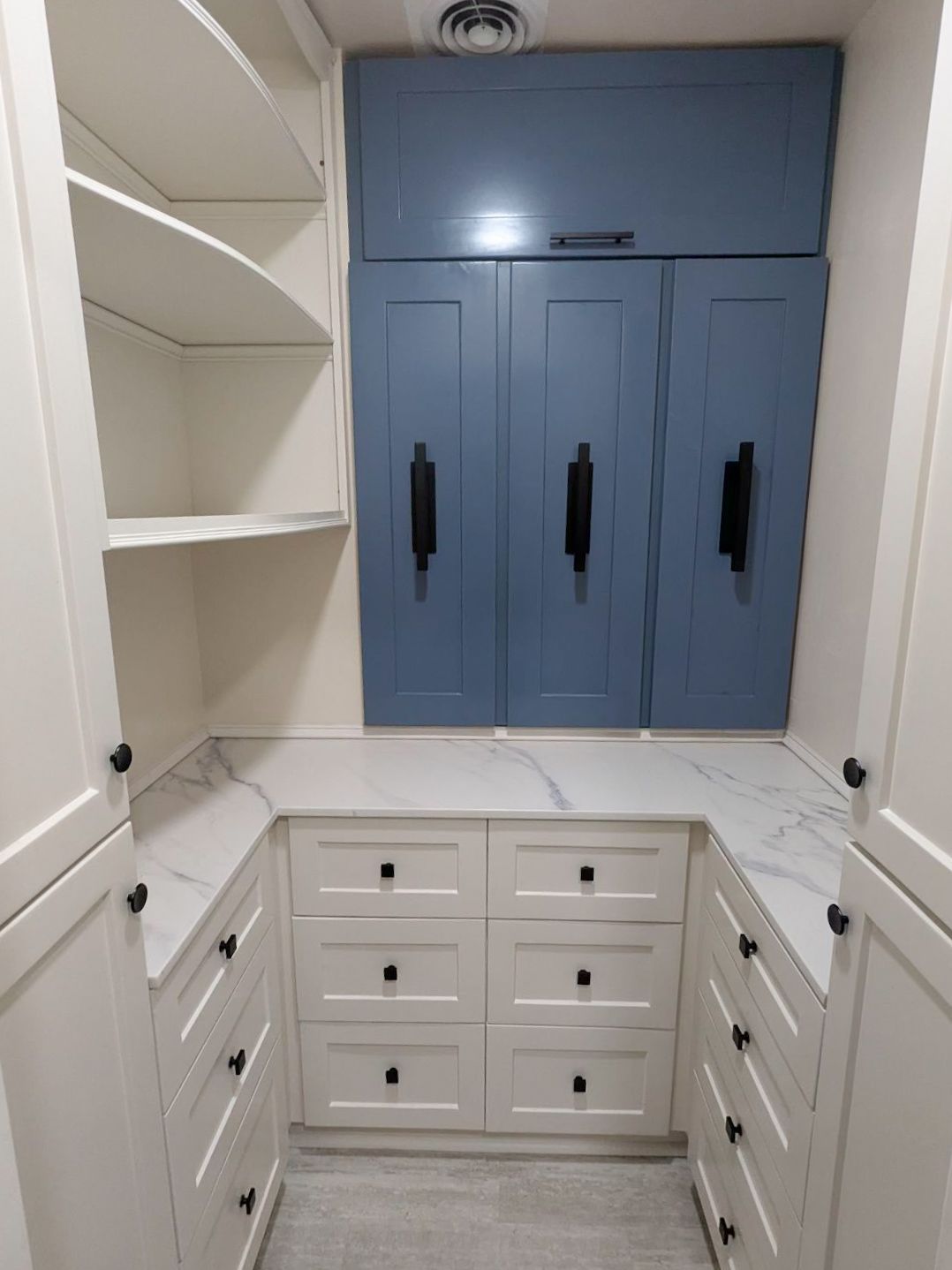 A walk in closet with white cabinets and blue doors