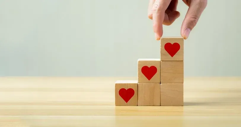 A person is stacking wooden blocks with hearts on them.