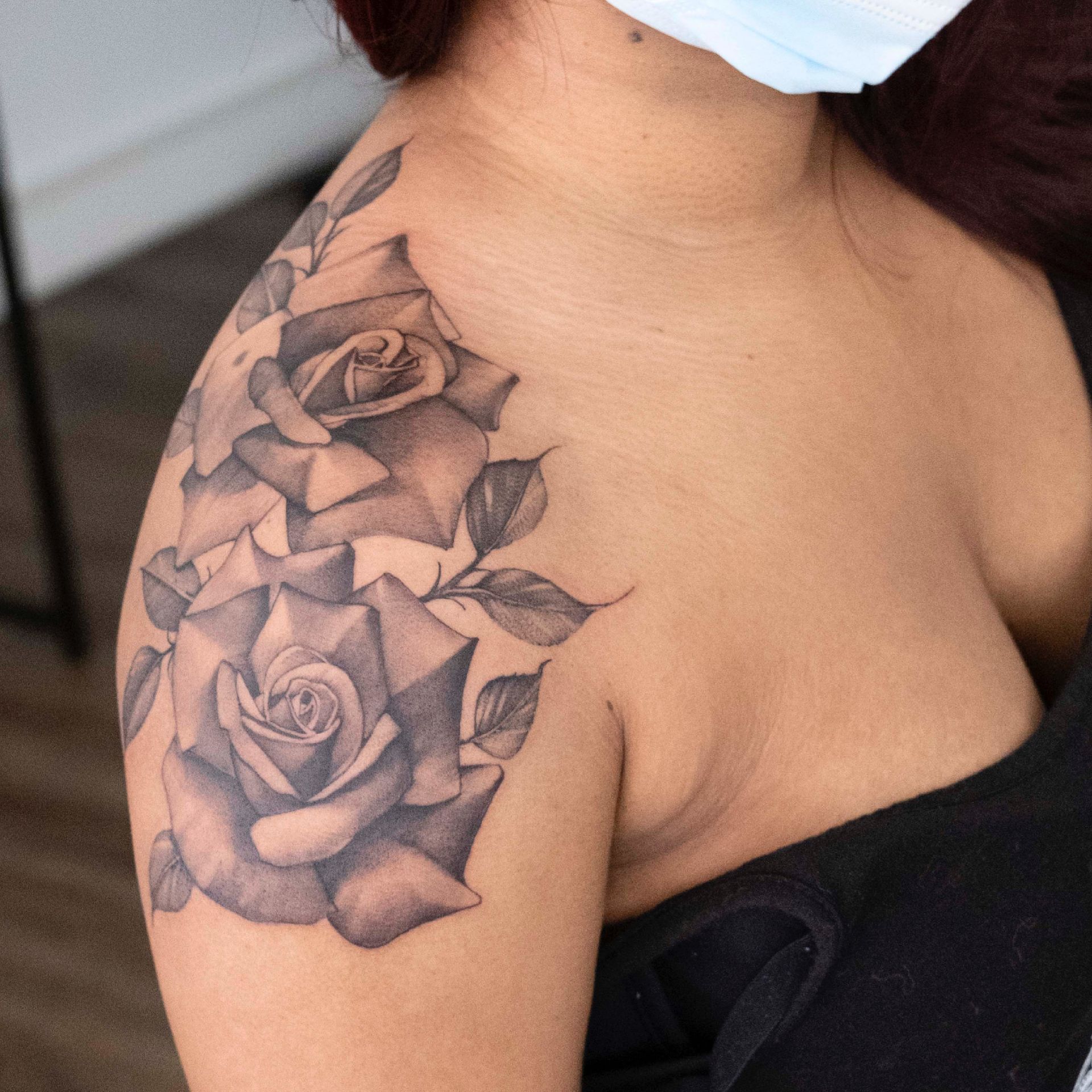 Eine Frau hat ein Tattoo von zwei Rosen auf ihrer Schulter