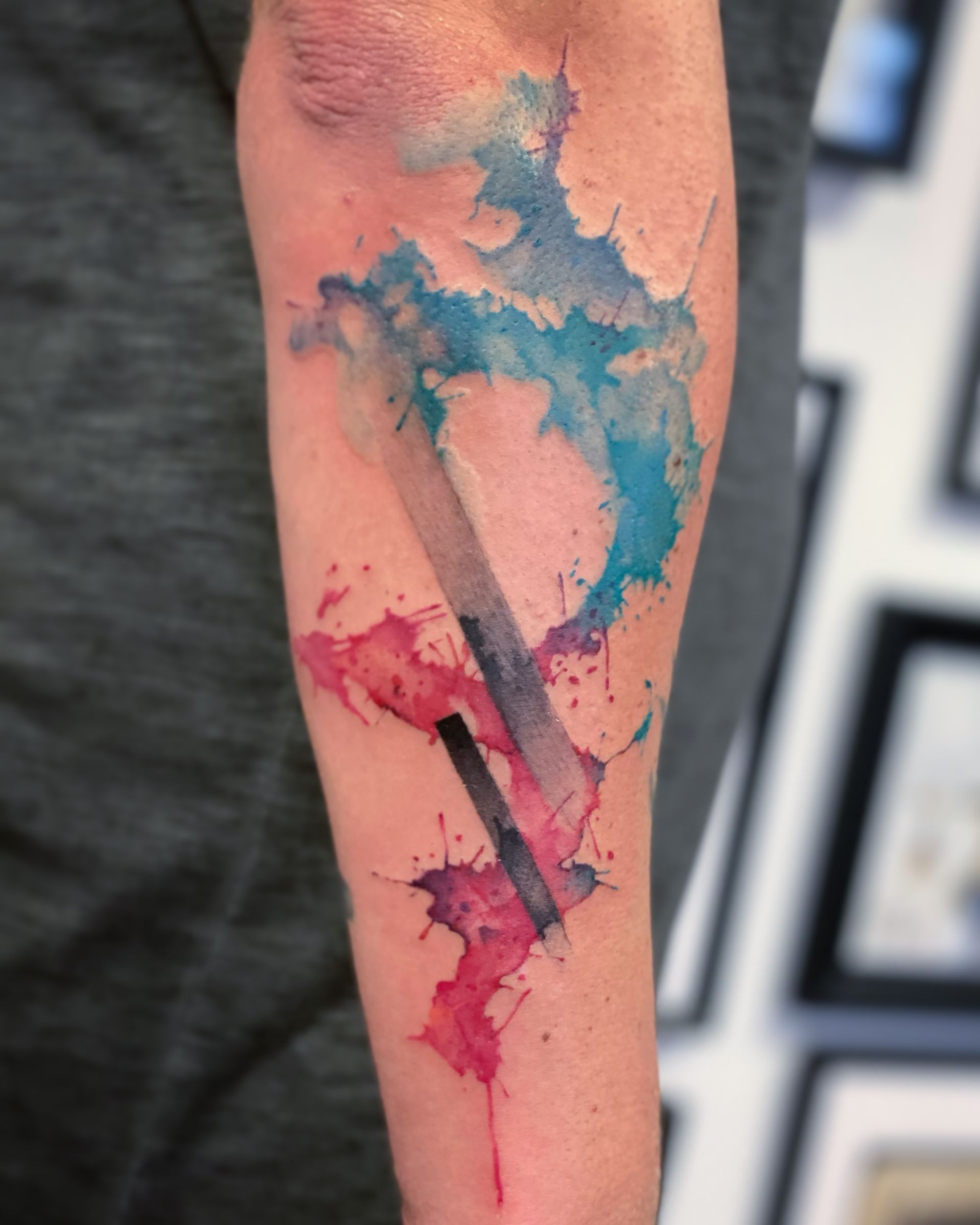 Eine Person hat ein Aquarelltattoo auf dem Arm